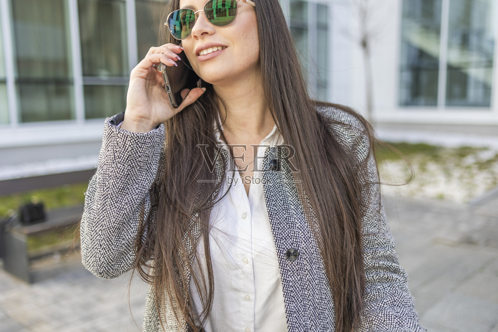 一位现代商业女性一边打电话一边骑着电动滑板车来上班。照片摄影图片