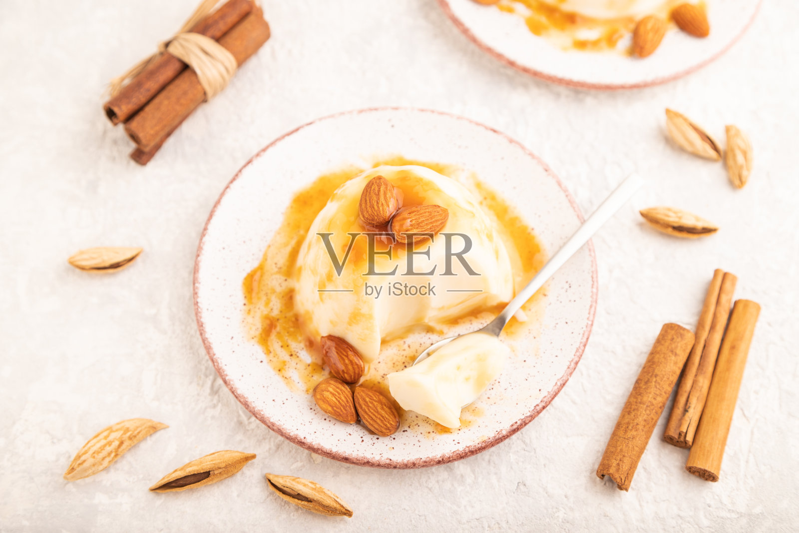 白色牛奶果冻配焦糖酱，灰色混凝土，侧视图，选择性聚焦。照片摄影图片