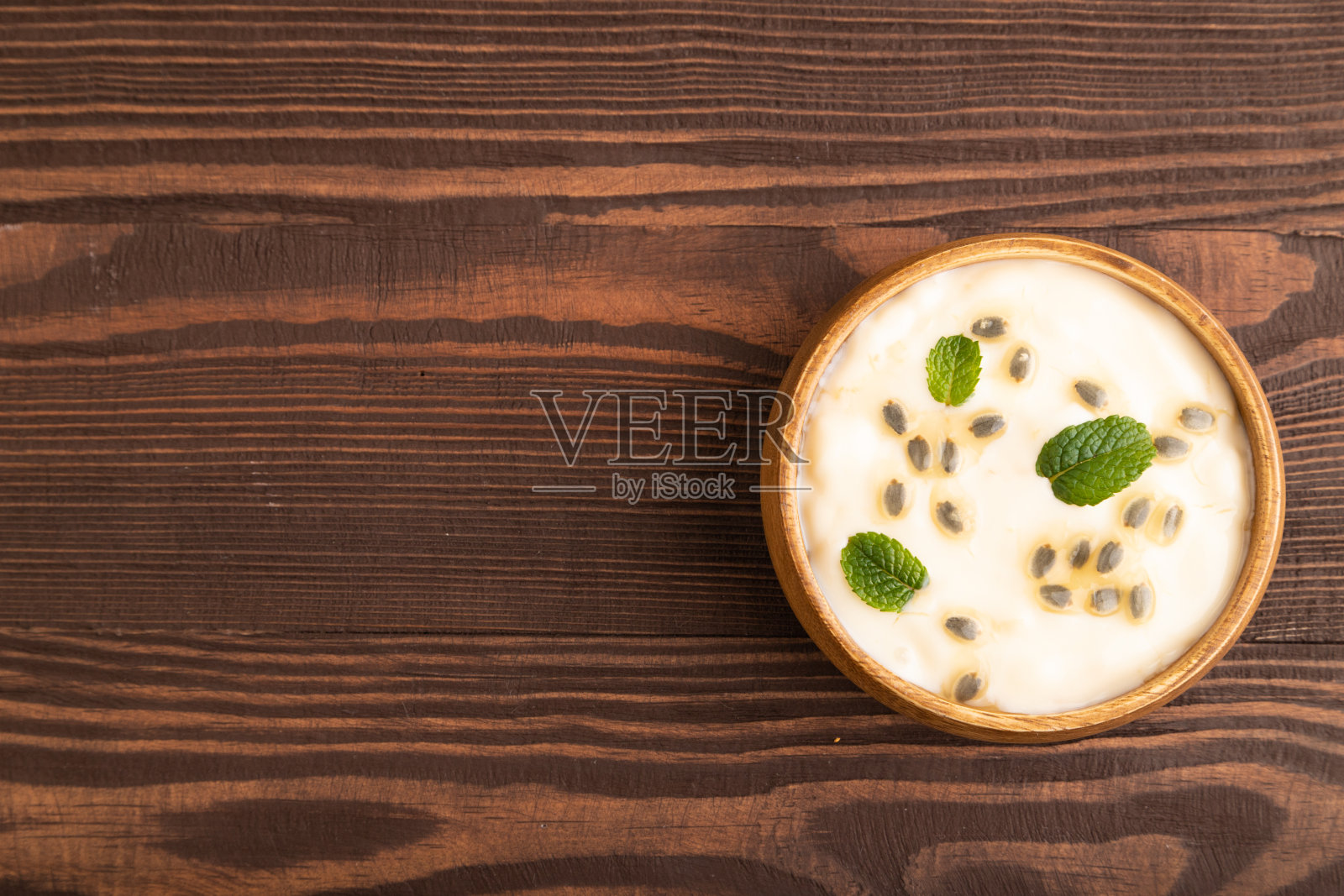 酸奶加麦片和薄荷，放在棕色木质的木碗里，俯视图，复制空间。照片摄影图片