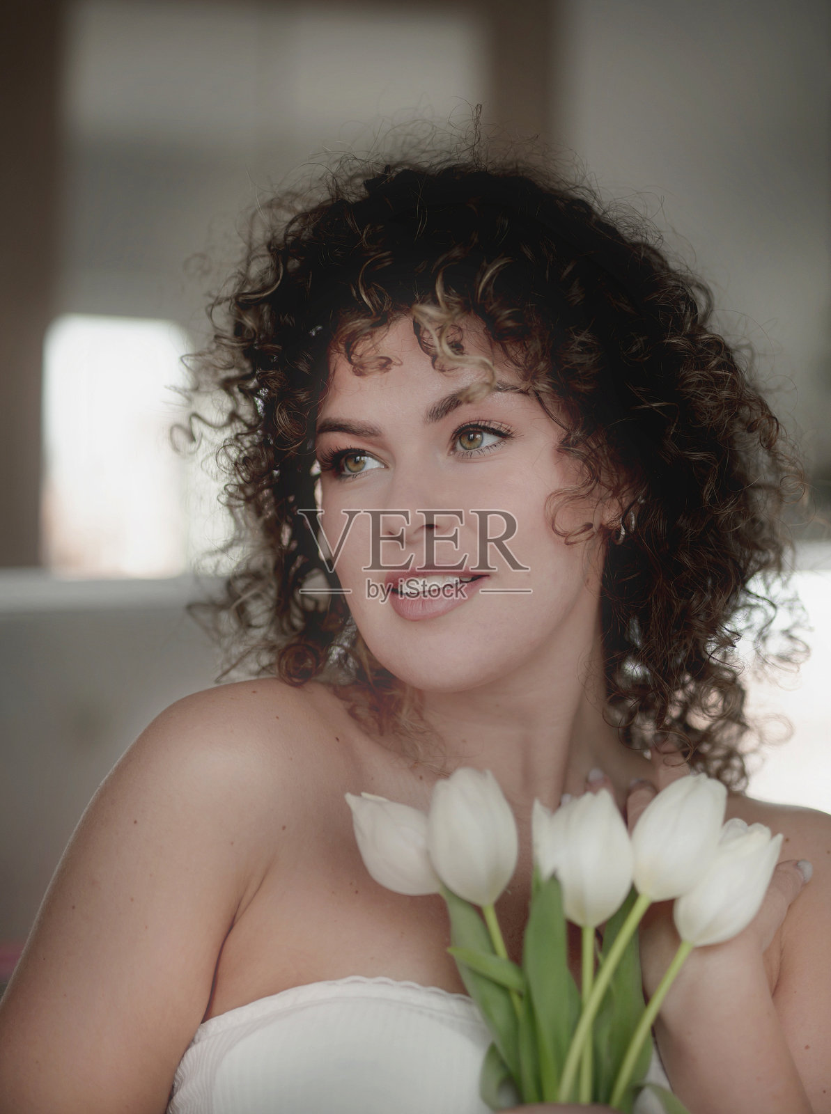 一位美丽的年轻女子捧着一束郁金香躺在镜子上照片摄影图片