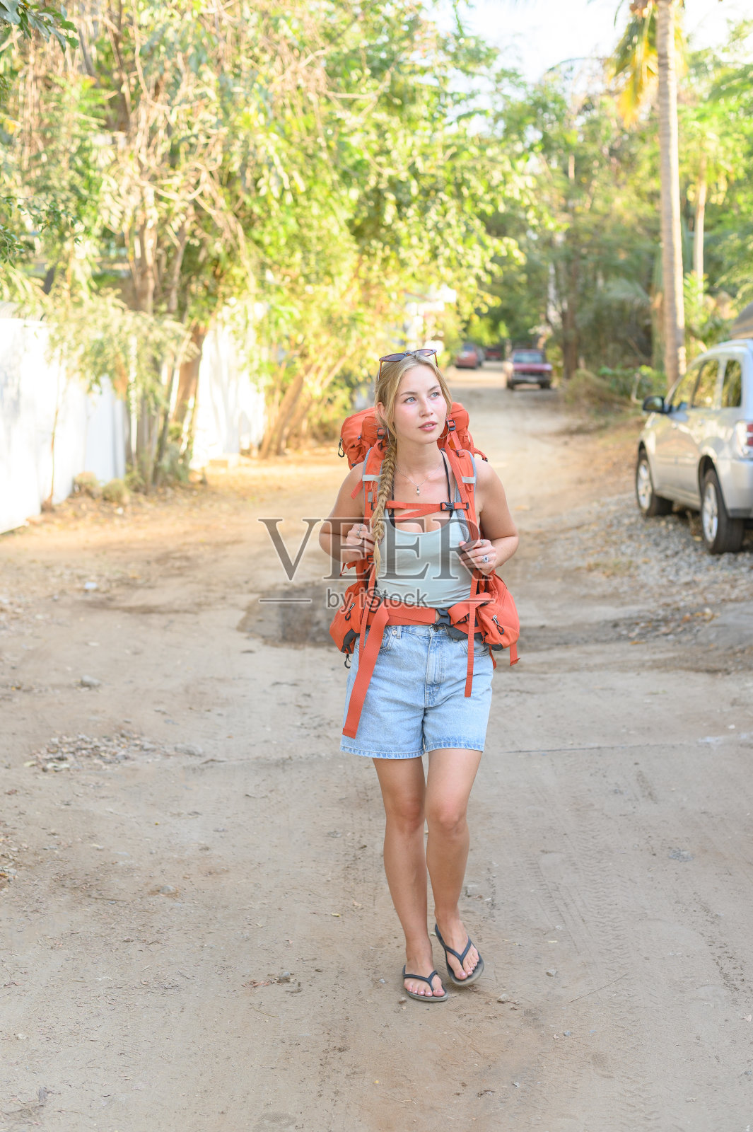 年轻的旅行女子背着背包走在肮脏的路上照片摄影图片