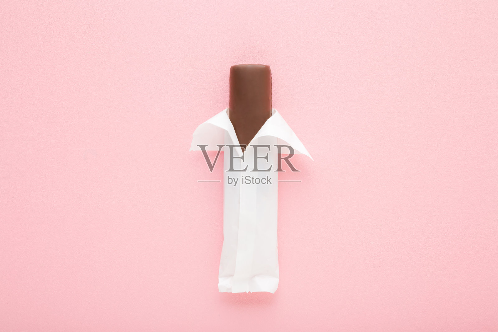 深棕色巧克力棒在浅粉色的桌子背景。柔和的颜色。特写镜头。白色开封的甜零食。自顶向下视图。照片摄影图片