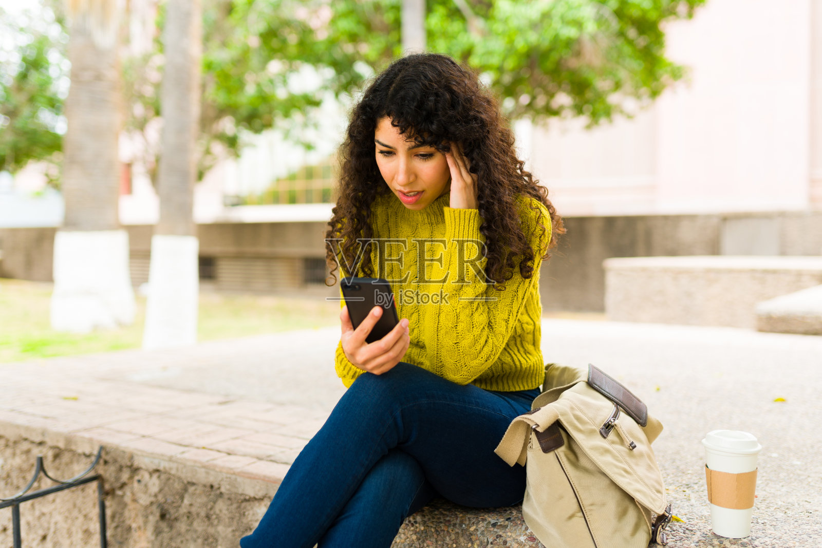 忧心忡忡的女人用智能手机发短信，看起来很有压力照片摄影图片