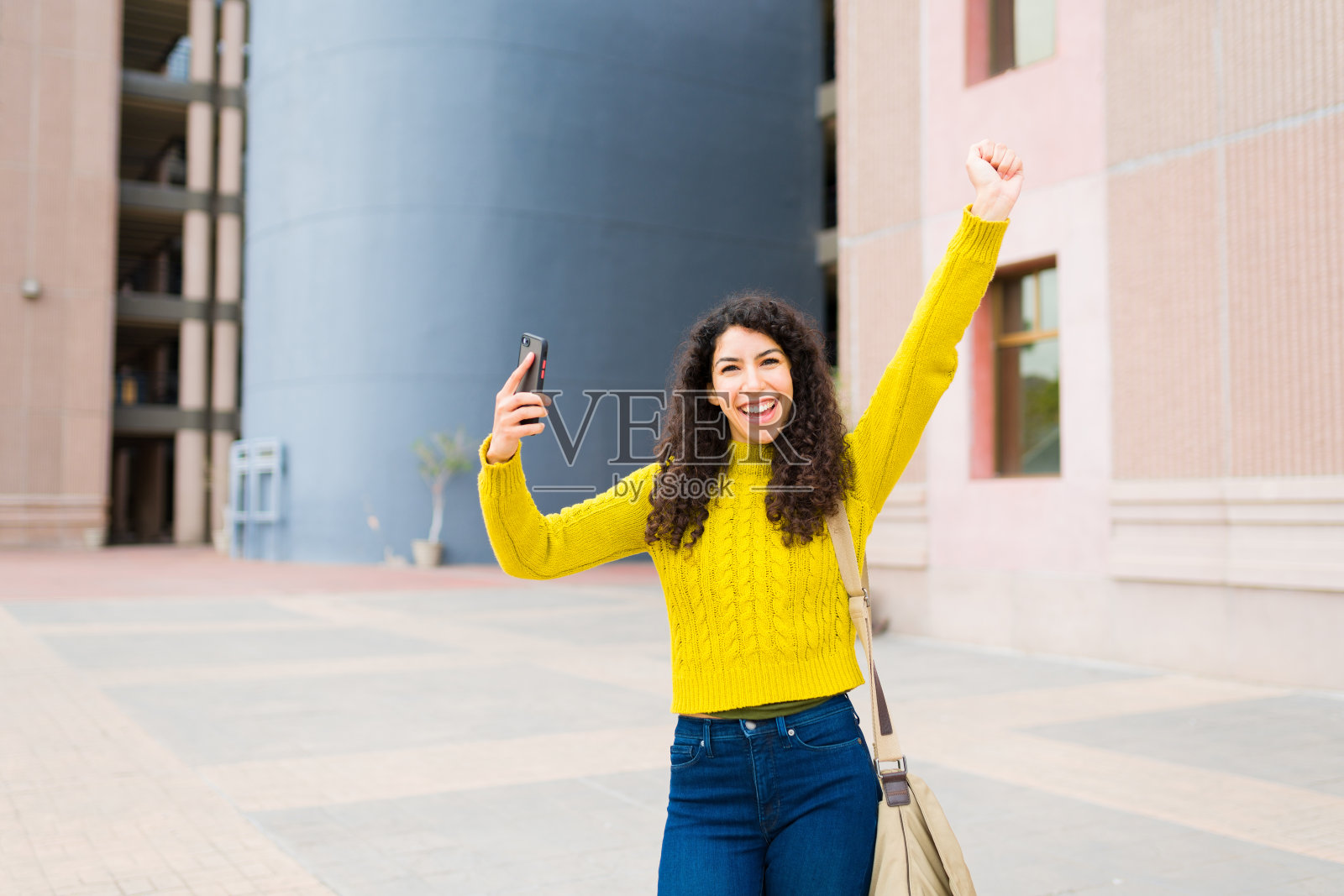 一个美丽的女人在户外用她的智能手机庆祝照片摄影图片