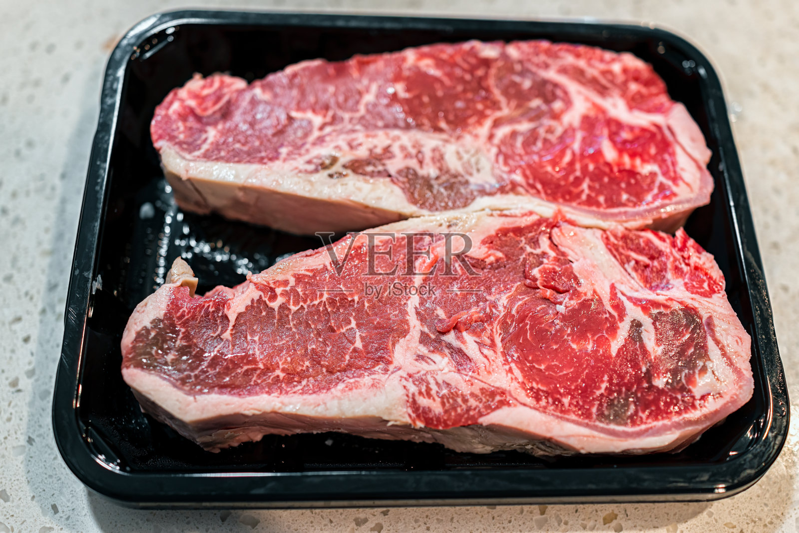 在厨房的塑料托盘上，两个红色的生牛排切肉的特写宏观纹理照片摄影图片