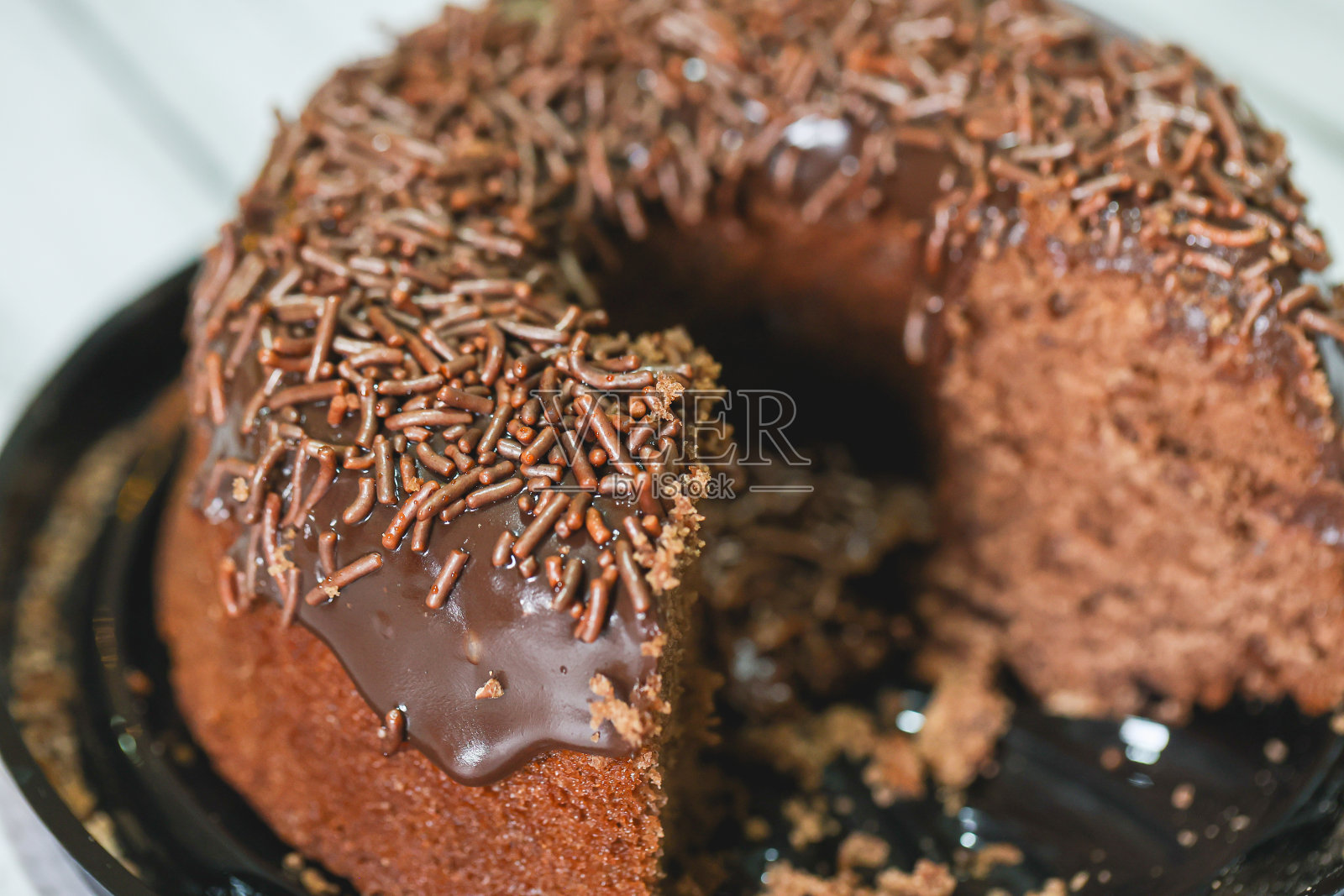 预先切好的巧克力蛋糕，上面有巧克力糖霜和巧克力粉装饰。黄板。在巴西，它被称为bolo de brigadeiro。木制的桌子。照片摄影图片