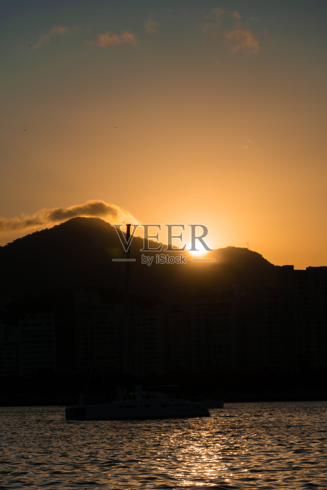 日落在瓜纳巴拉湾，海湾和海滩里约热内卢里约热内卢，巴西的建筑，船只和景观。海中天空的倒影照片摄影图片