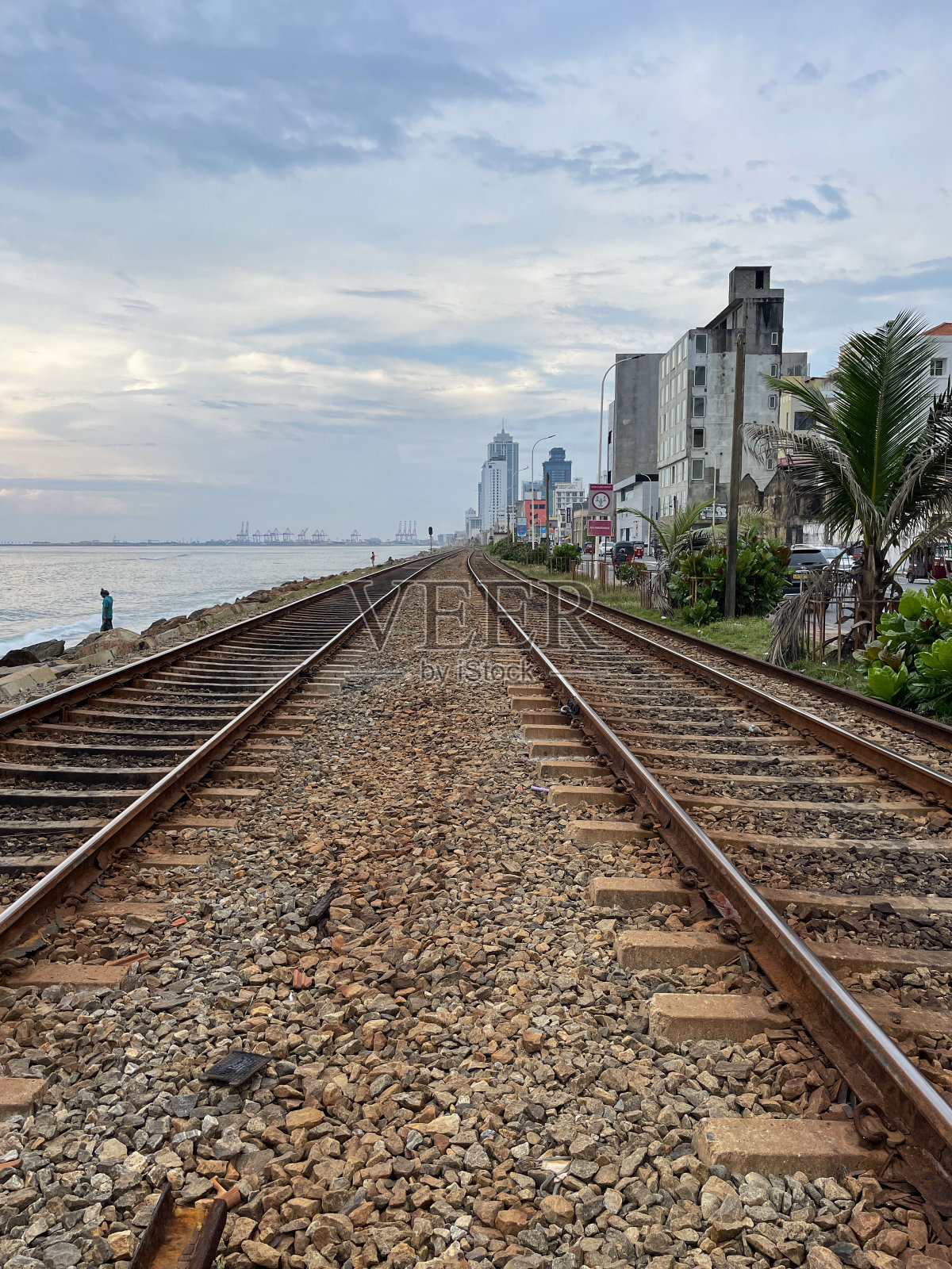 斯里兰卡科伦坡，与高速公路和海岸线平行的海岸线(南线)铁路线特写，金属铁轨和碎石，主要道路上的机动车包括汽车，高架视图，递减视角照片摄影图片
