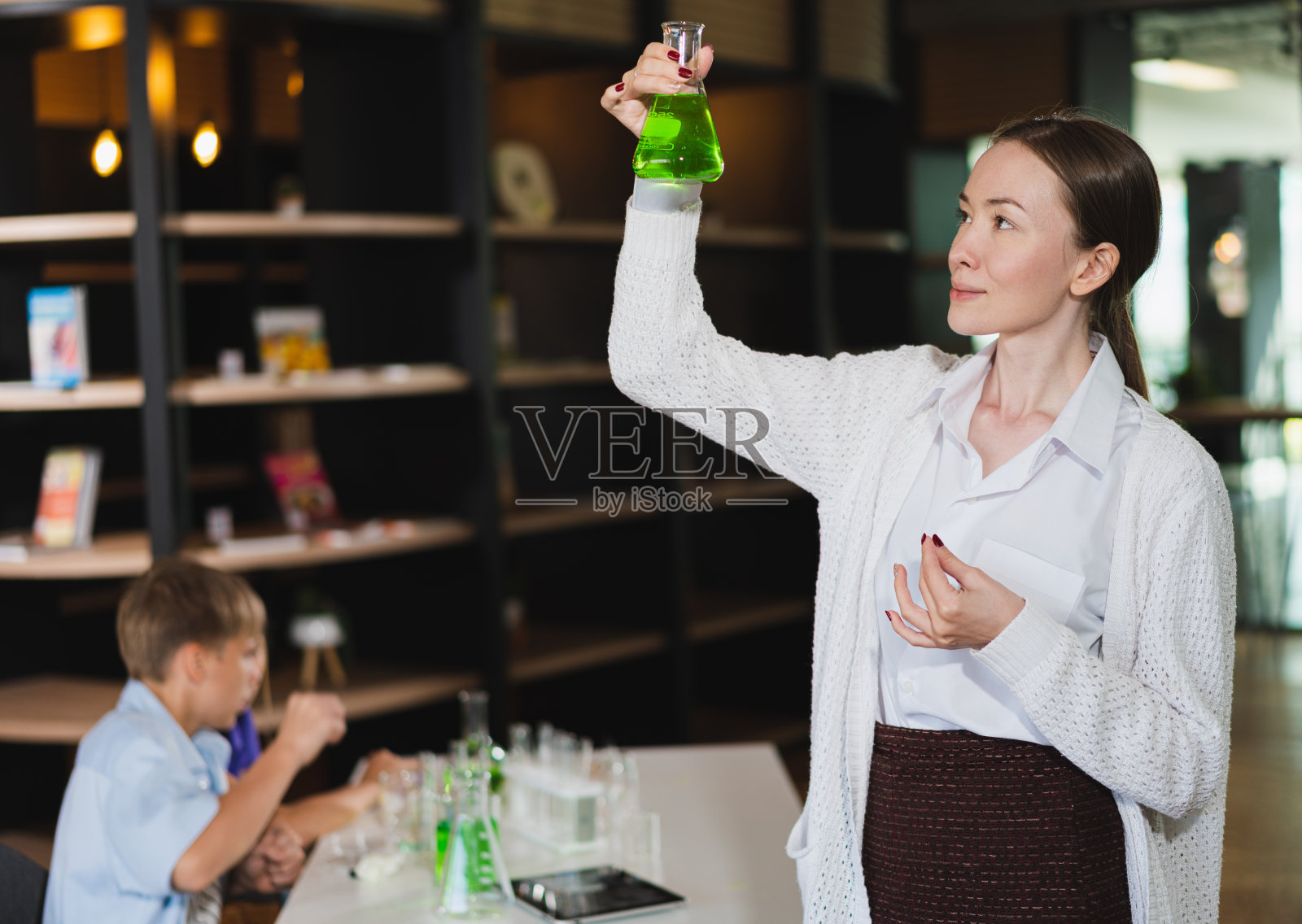 白人老师用化学试管教白人男孩照片摄影图片