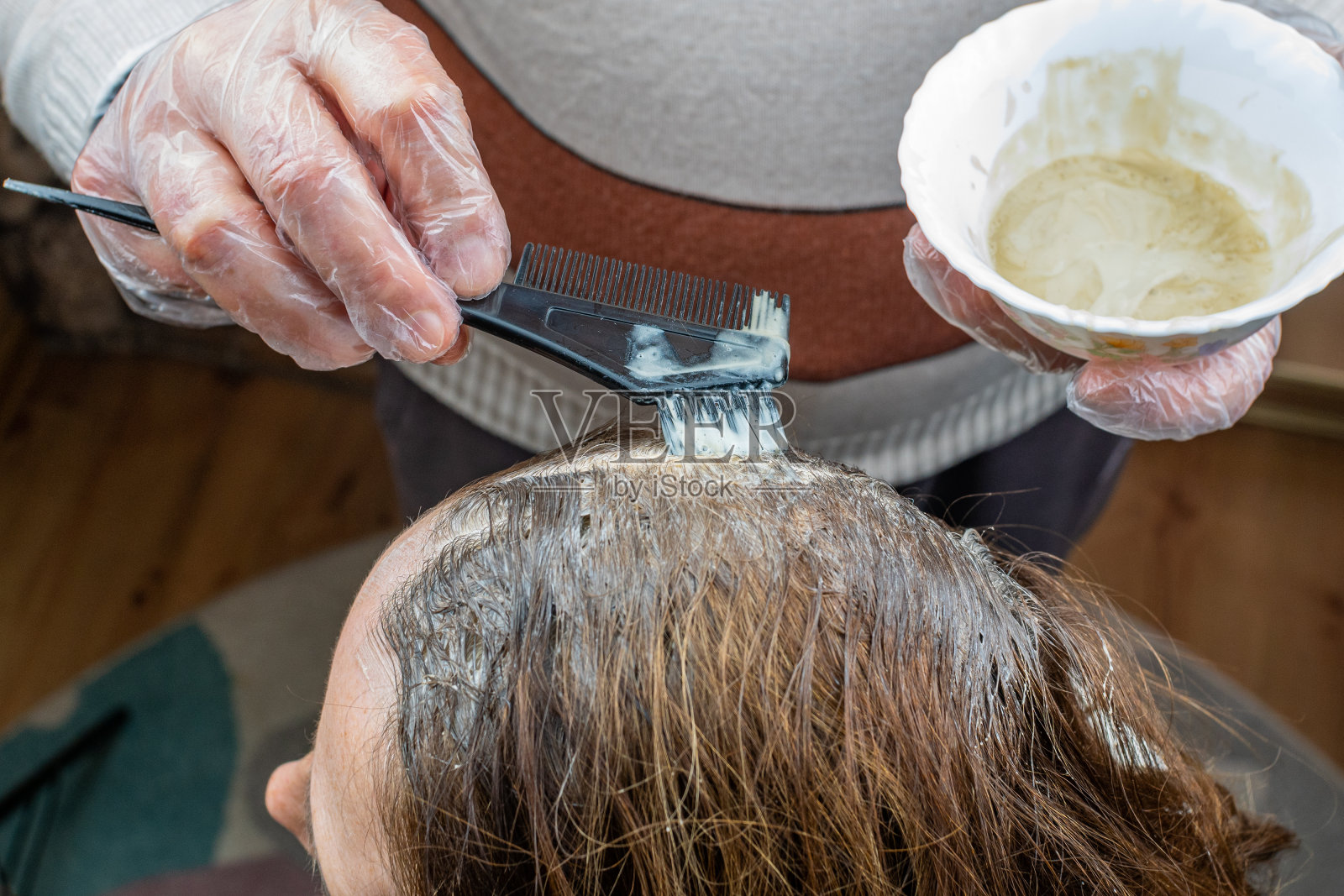 给女人的头发上色。染发特写。男主人用刷子把客户的头发染成化学颜料。一个成年妇女灰色的发根。美发服务理念照片摄影图片