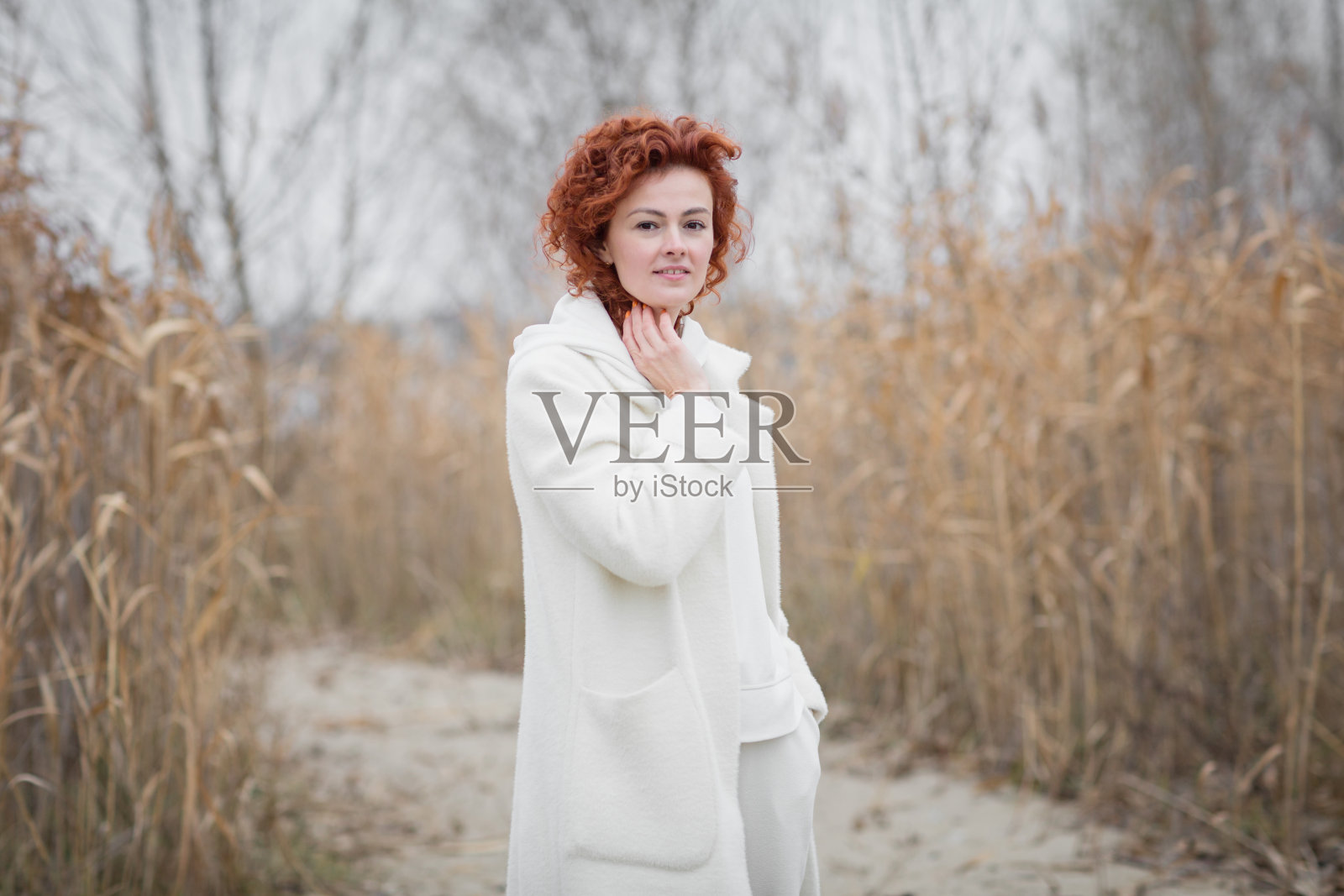 有吸引力的时尚女人拿着干芦苇走在公园里照片摄影图片