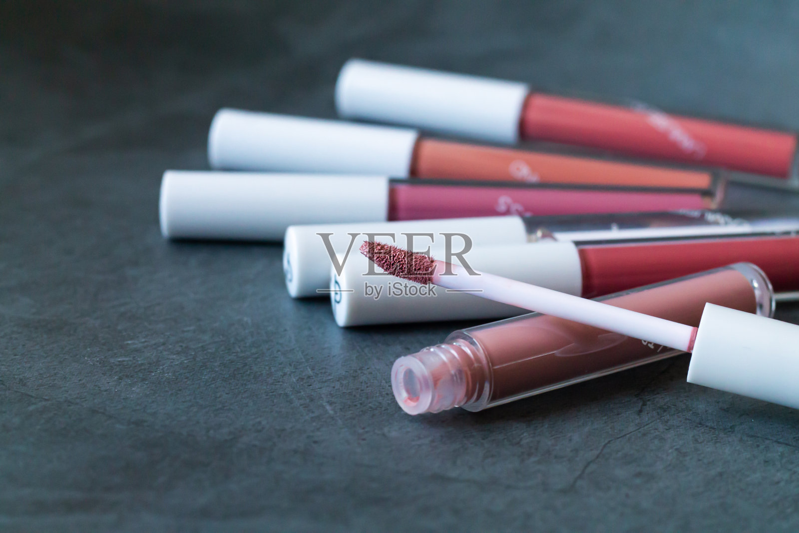 液体口红或唇彩，开口管在石头背景照片摄影图片