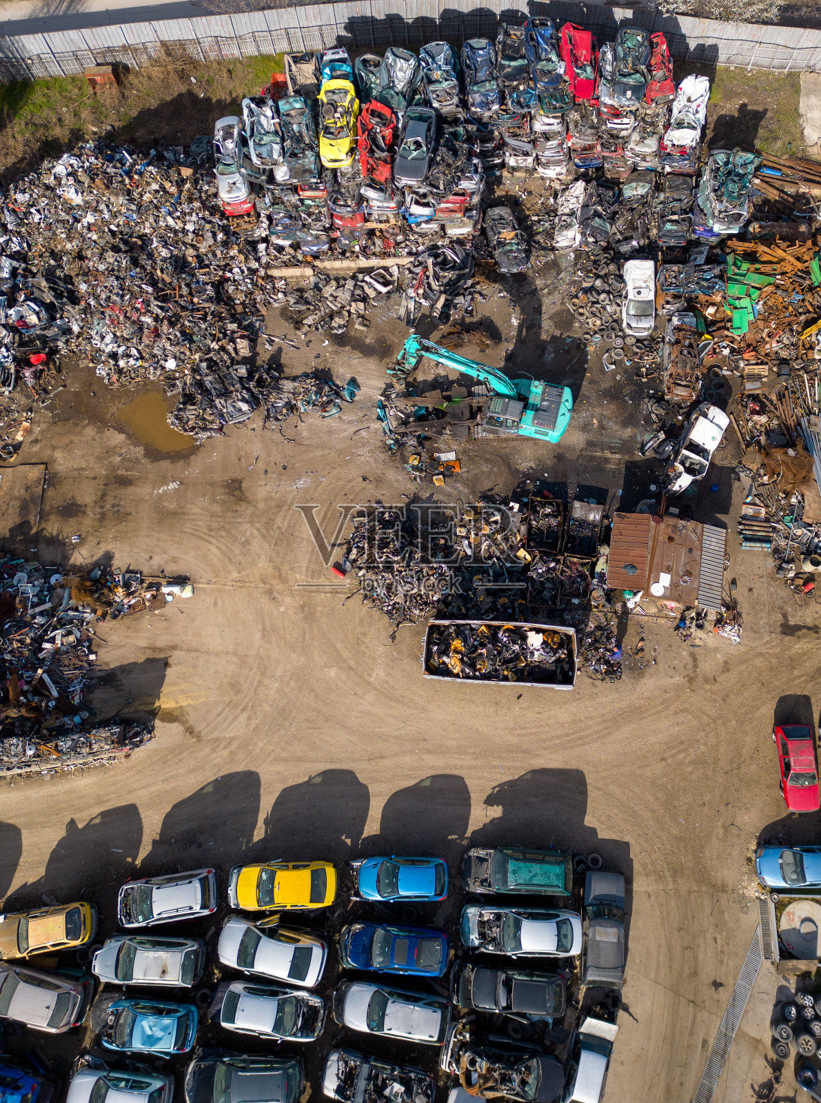 汽车垃圾场的鸟瞰图，在那里可以看到一台机器将旧汽车分离成碎片。照片摄影图片