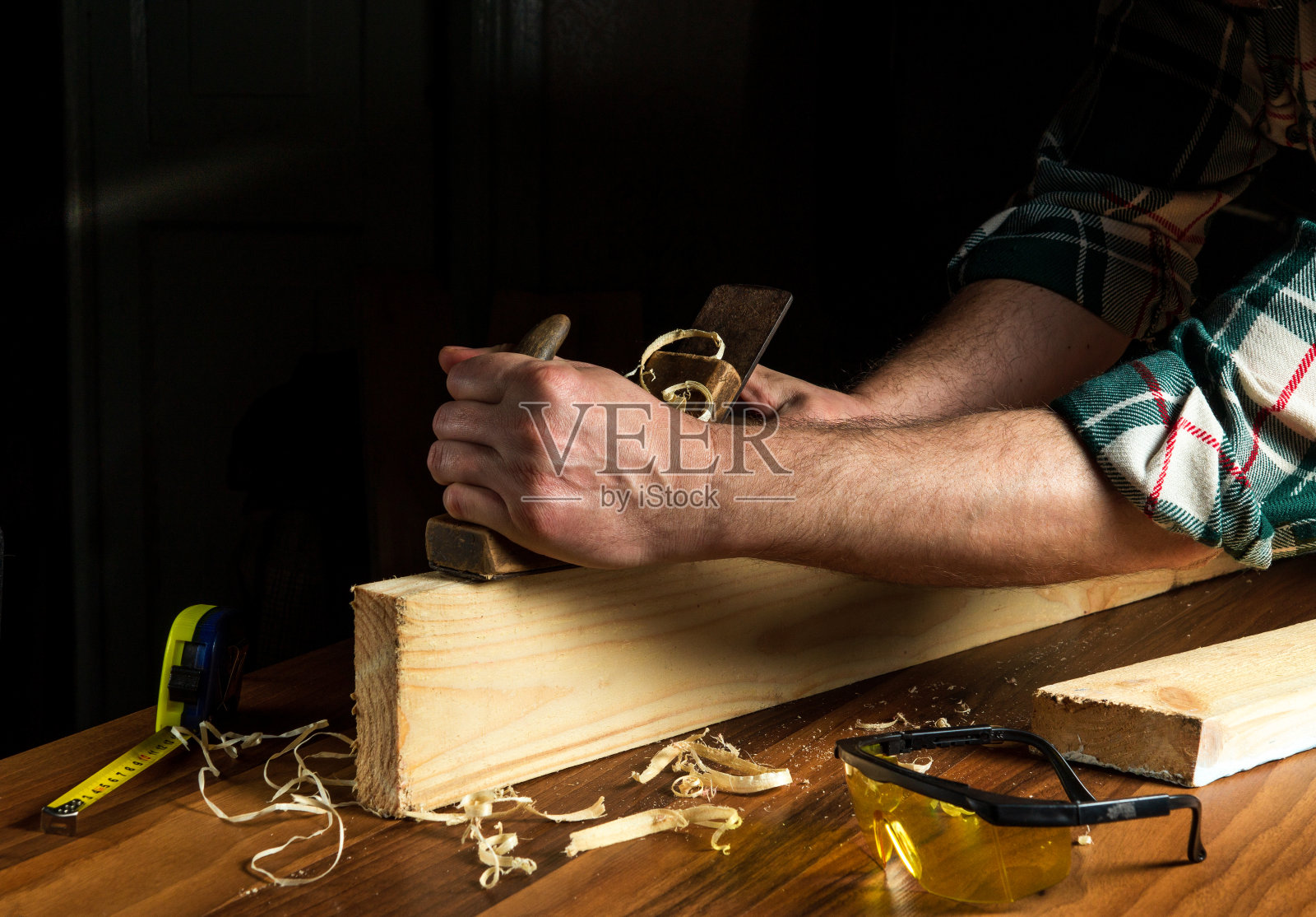 木工用手刨清理木板。大师的手在工作中特写。木工车间的工作环境照片摄影图片
