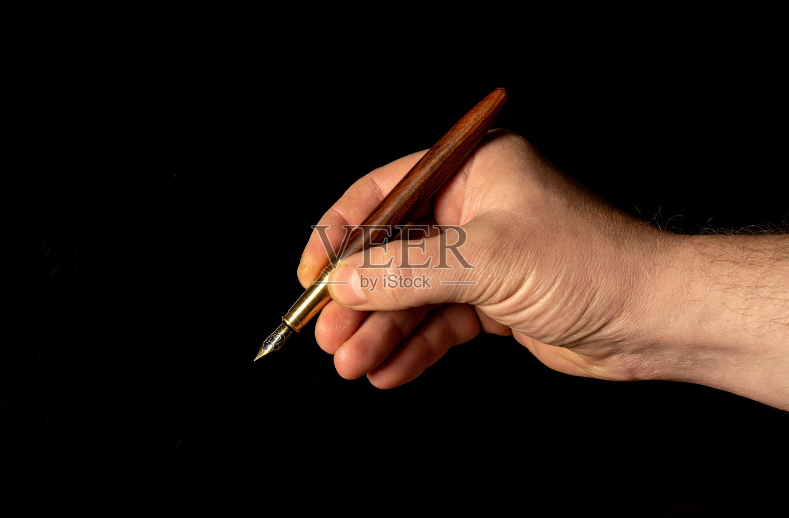 特写男性用笔写字，手里拿着笔，孤立在黑色背景上。文件包含有剪切路径，便于工作照片摄影图片
