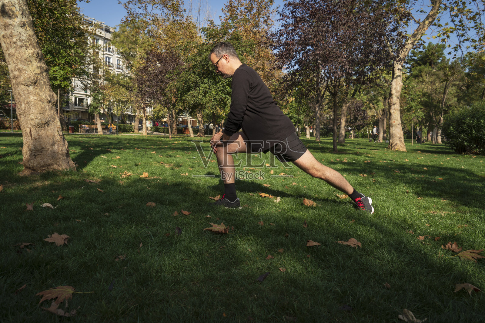 成年男子慢跑前在公园里伸展身体照片摄影图片