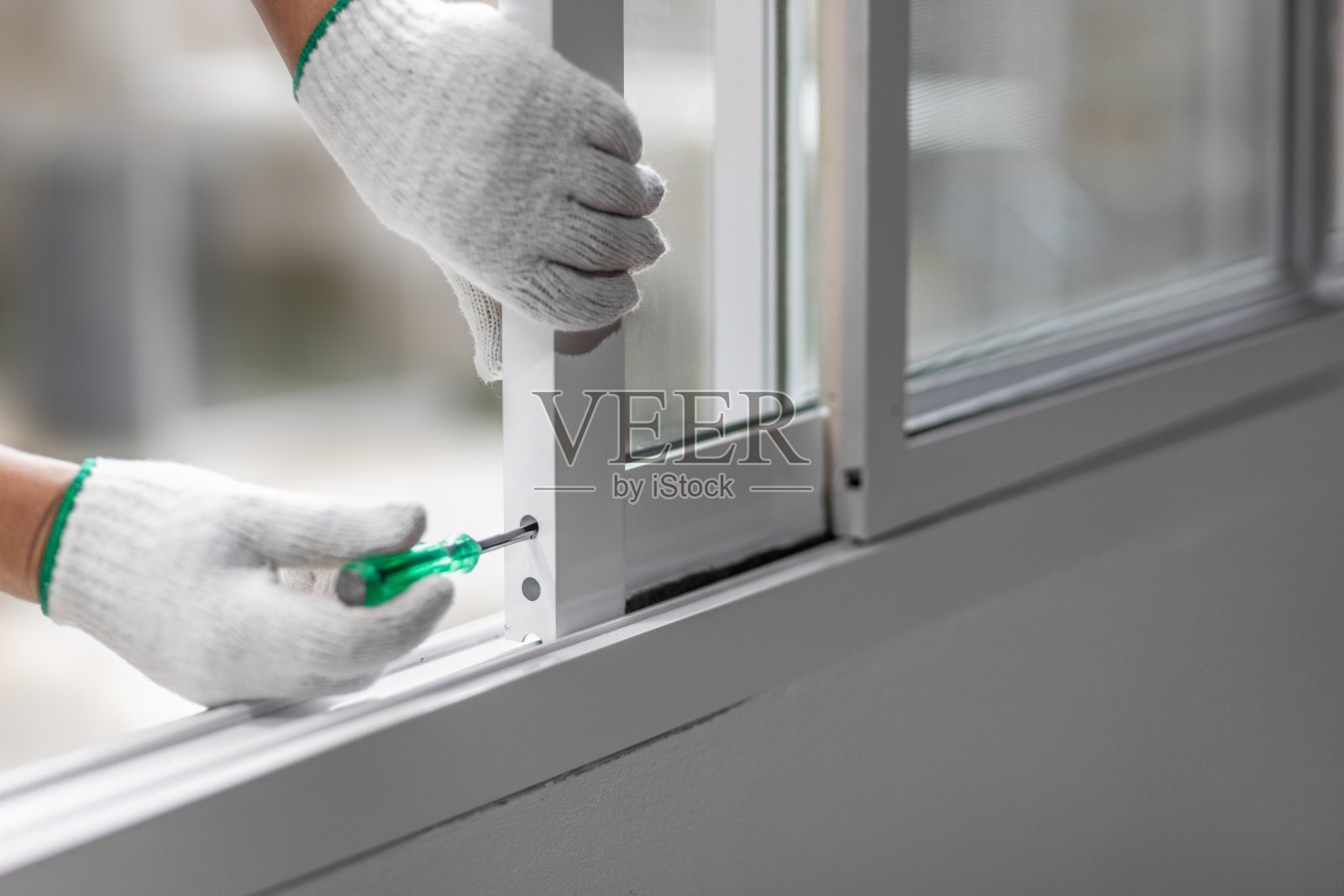 建筑工人正在修理滑动窗。打开调整轨道轮盖。照片摄影图片