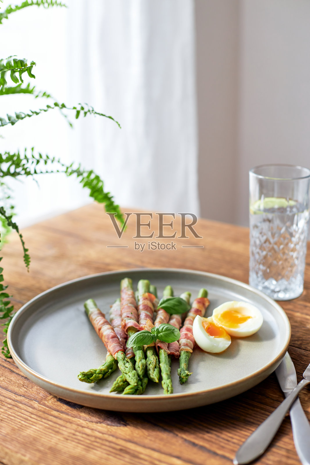 新鲜芦笋裹培根烤，配上鸡蛋卷。健康食品。照片摄影图片