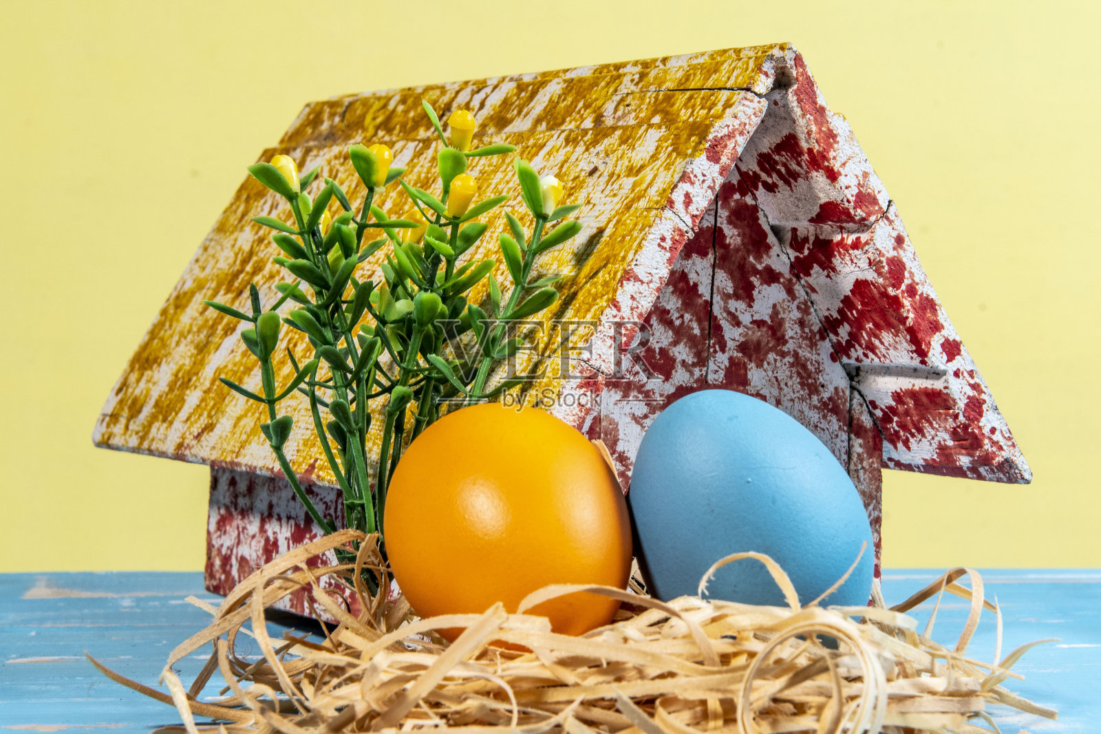 五颜六色的彩蛋象征着复活节，带着玩具屋，鲜花像花园照片摄影图片