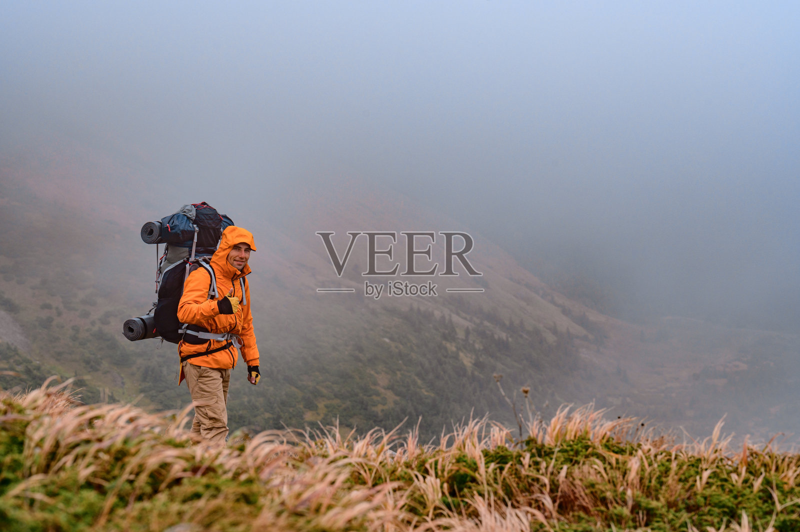 一个男人在雾中爬山，一个男人背着背包。照片摄影图片