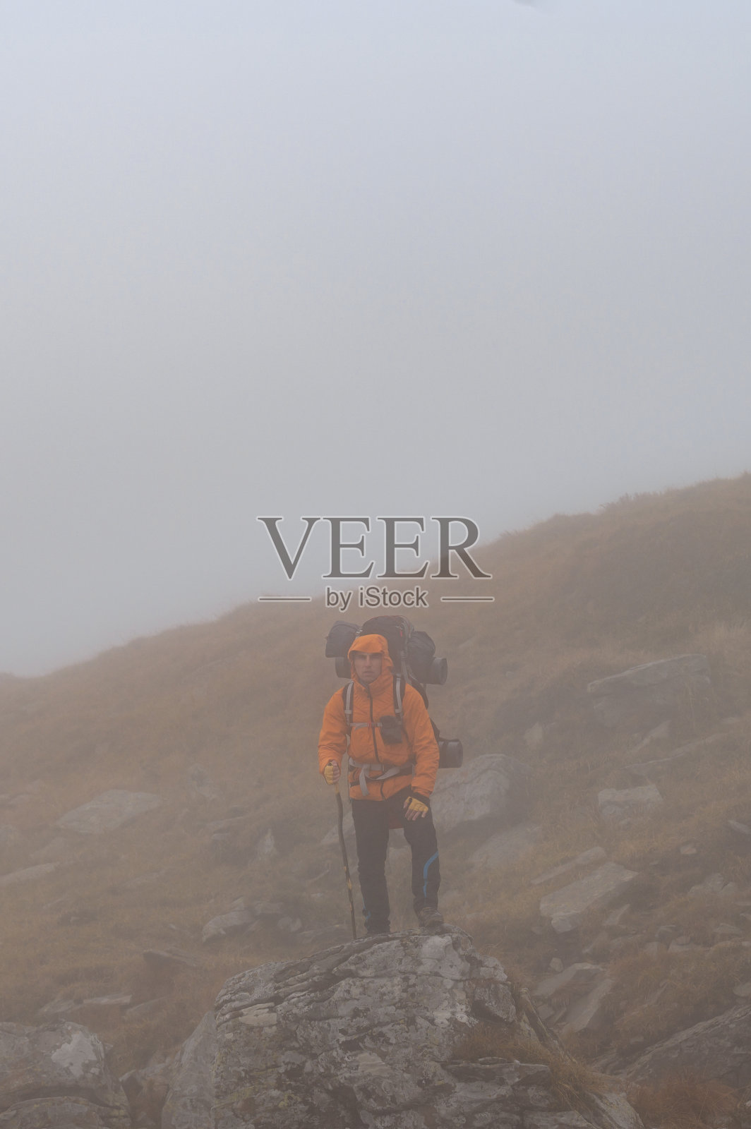 乌克兰喀尔巴阡山脉，一名徒步旅行的男子背着背包，沿着一条布满岩石的小路爬上山顶。照片摄影图片