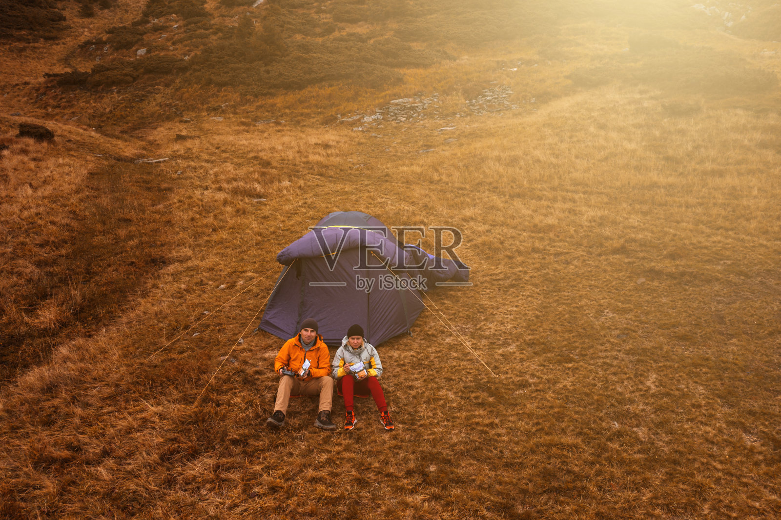 两名游客坐在Hoverla山下的帐篷旁，散步后吃午饭。照片摄影图片