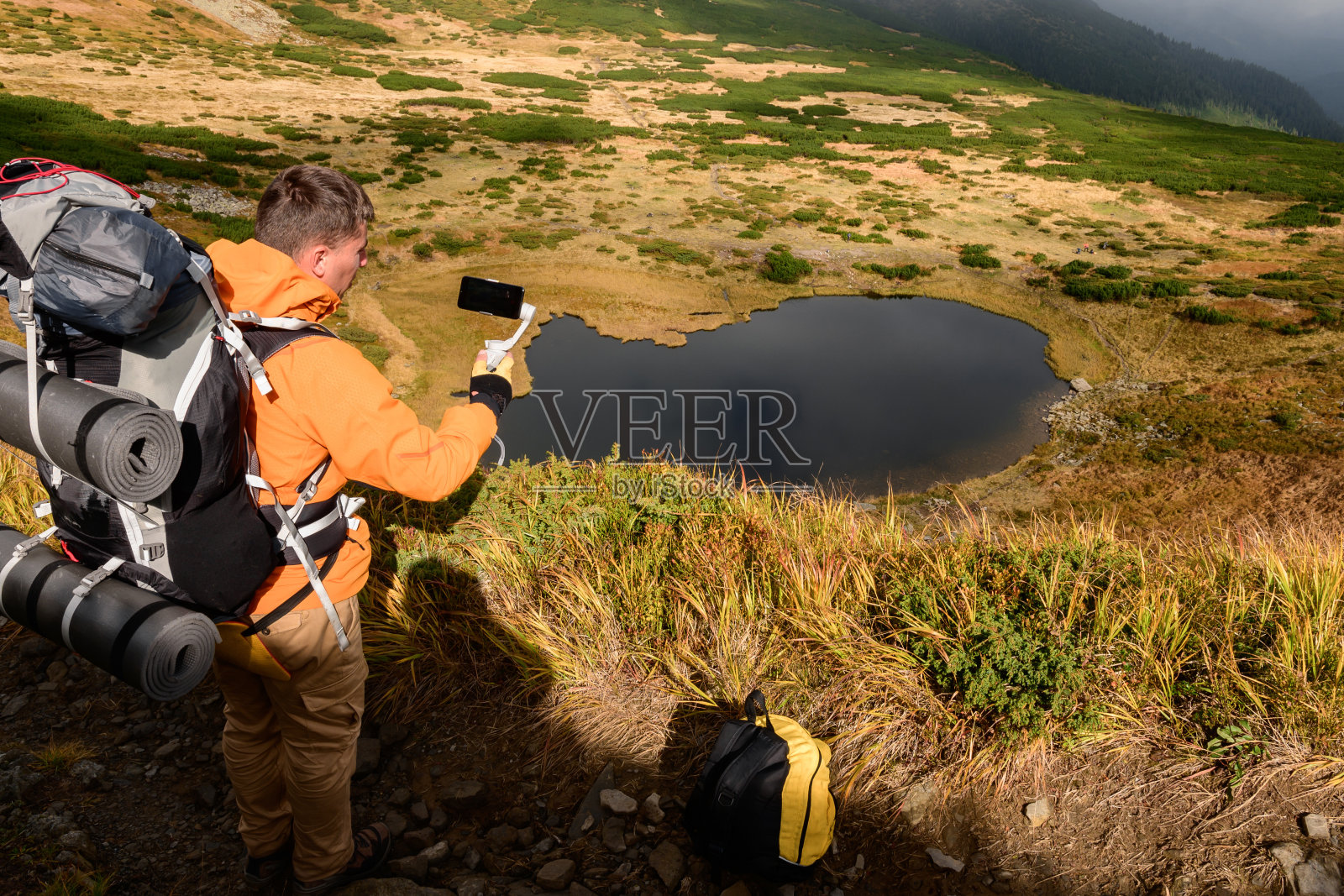 游客坐在高山上的草地上，背景是内萨莫夫特湖，游客和内萨莫夫特湖，湖边的秋天景色。照片摄影图片
