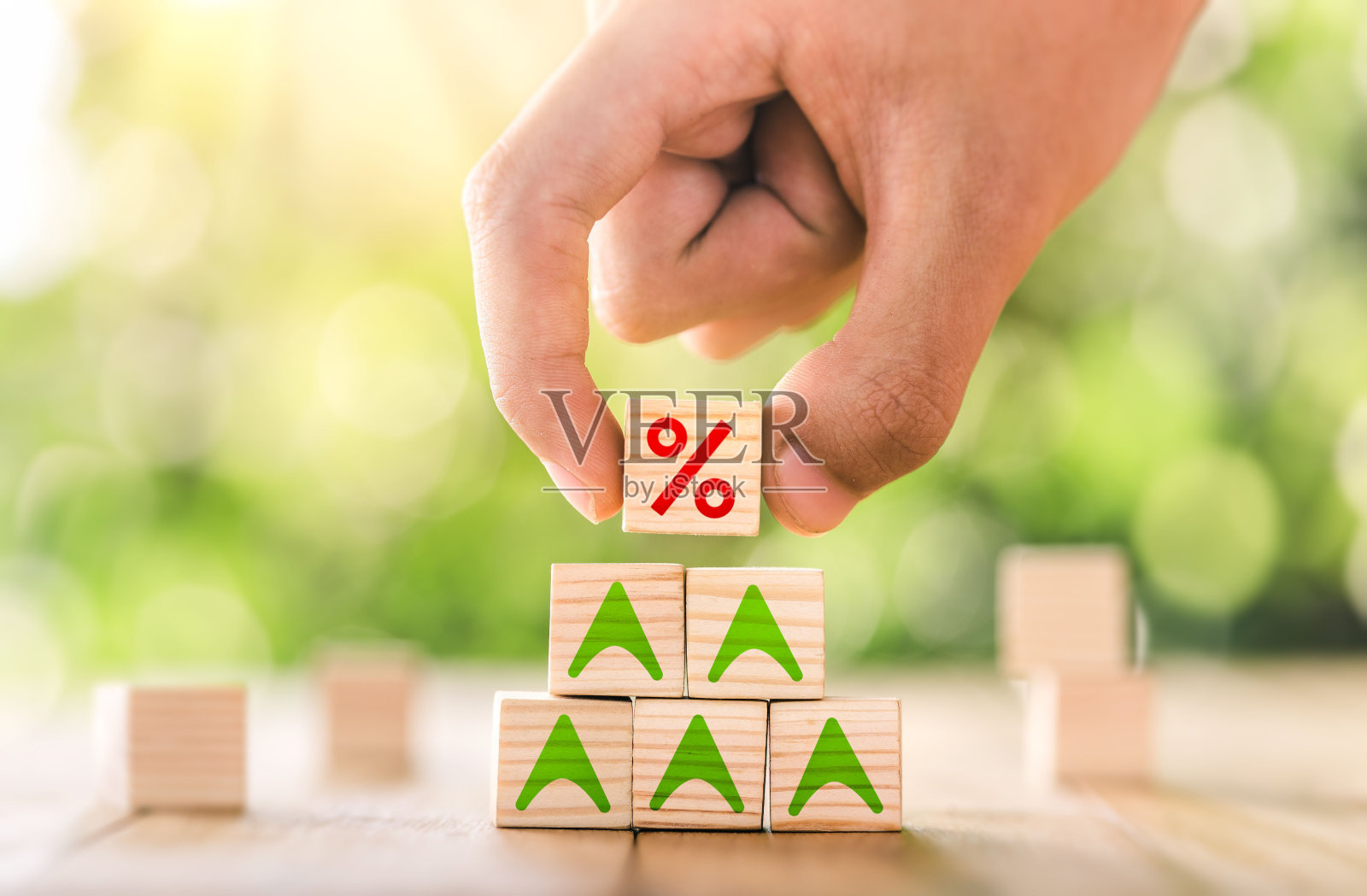 利率金融和抵押贷款利率概念。用手将木块放在顶部，向上增加图标百分比符号。照片摄影图片