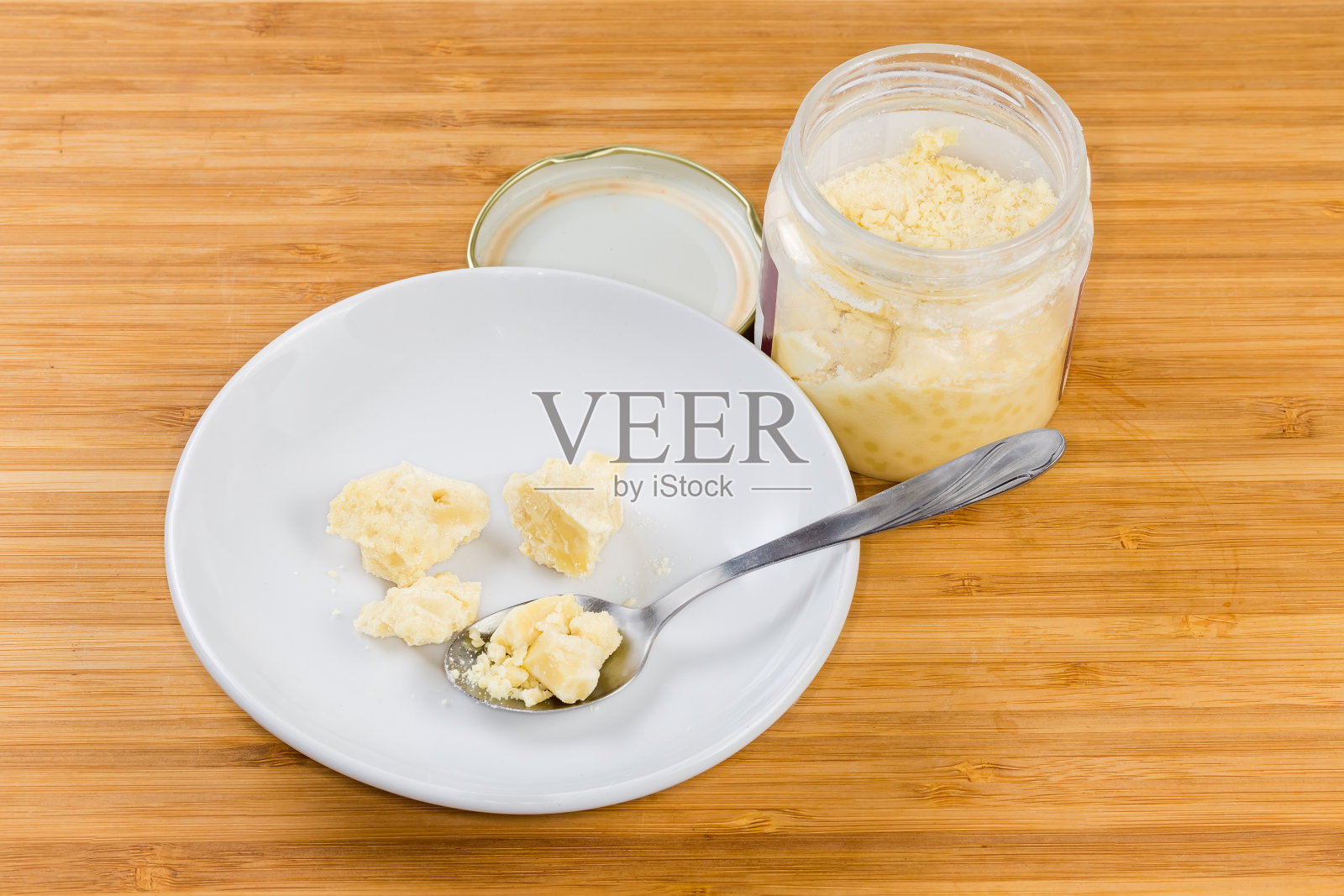 将可可脂涂在茶托上，并将其装在木质表面的罐子里照片摄影图片