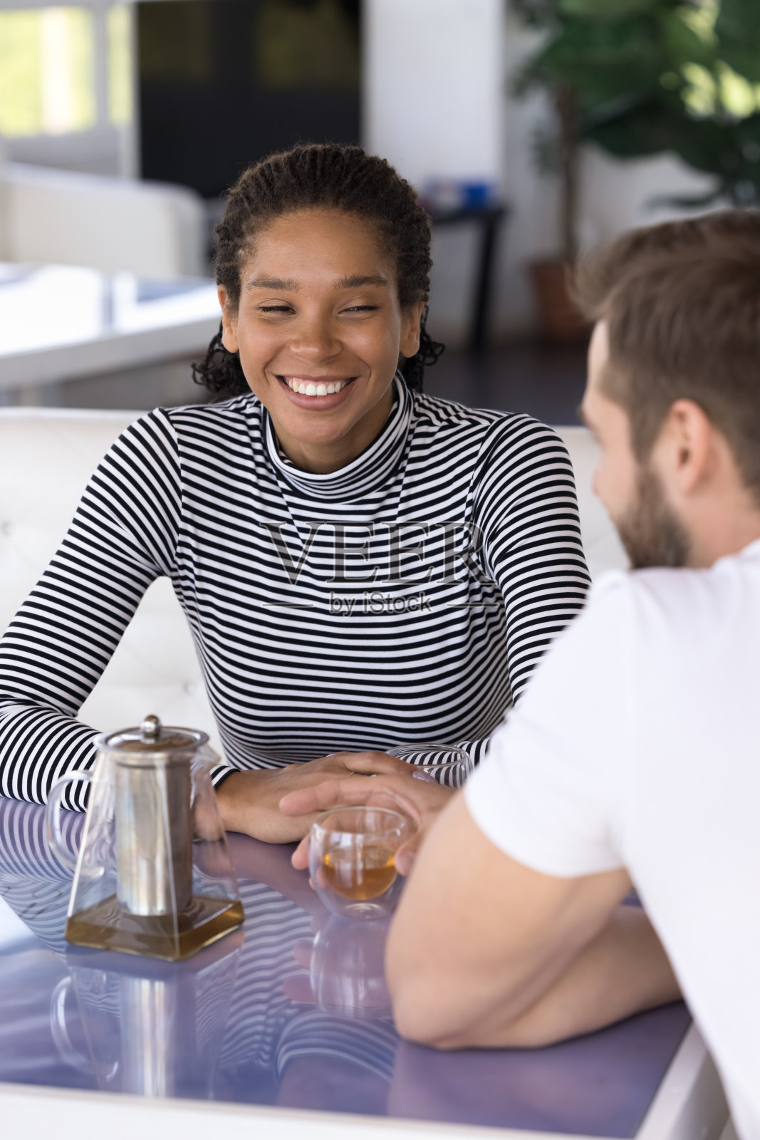 快乐美丽的年轻黑人女孩坐在咖啡馆的桌子上，照片摄影图片