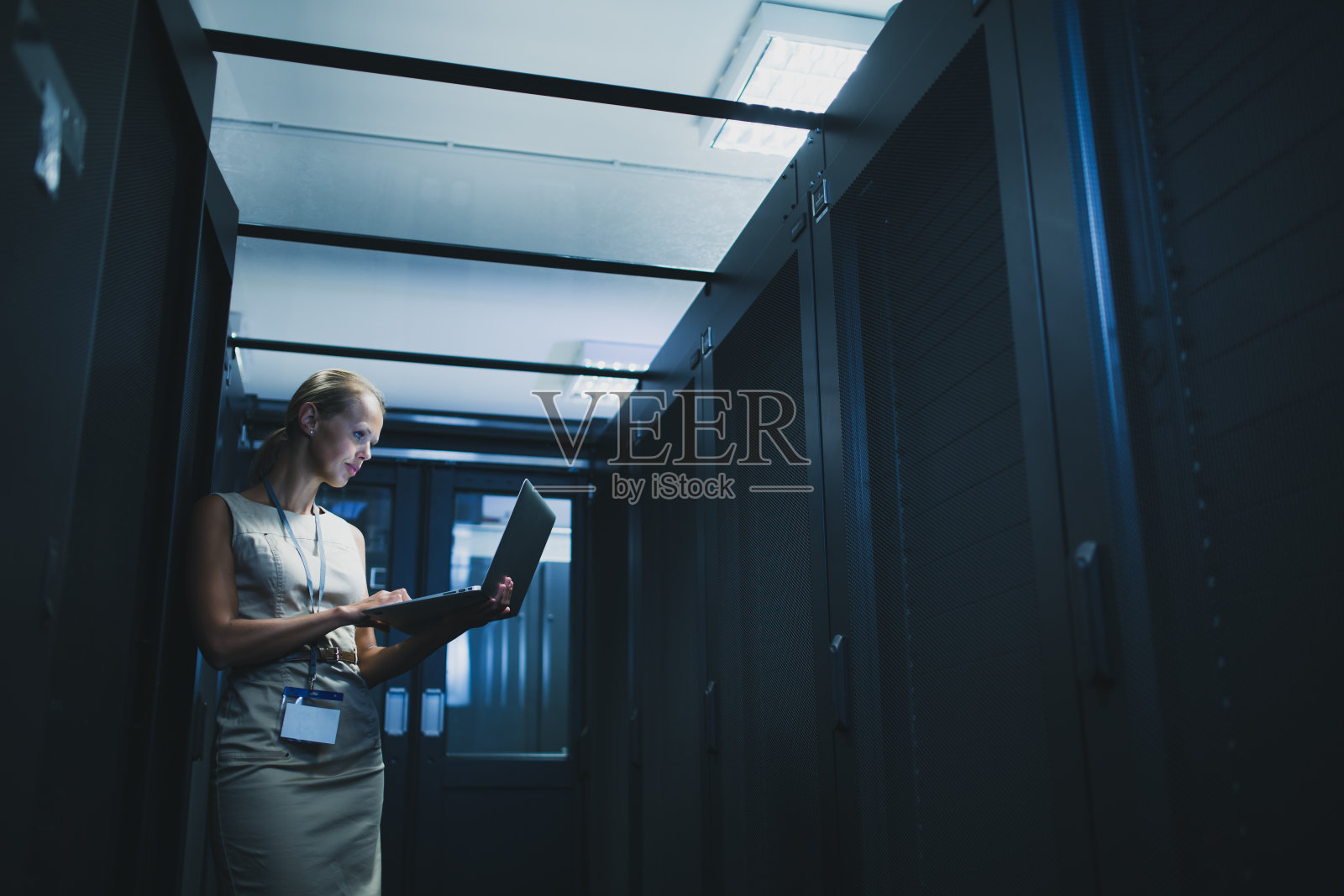 IT工程师站在工作的服务器机架前进行例行维护检查照片摄影图片