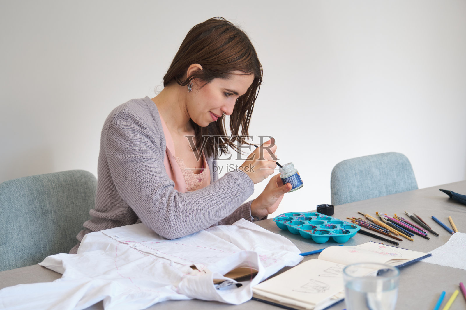 白种人妇女用丙烯酸颜料在白衬衫上手绘设计。照片摄影图片