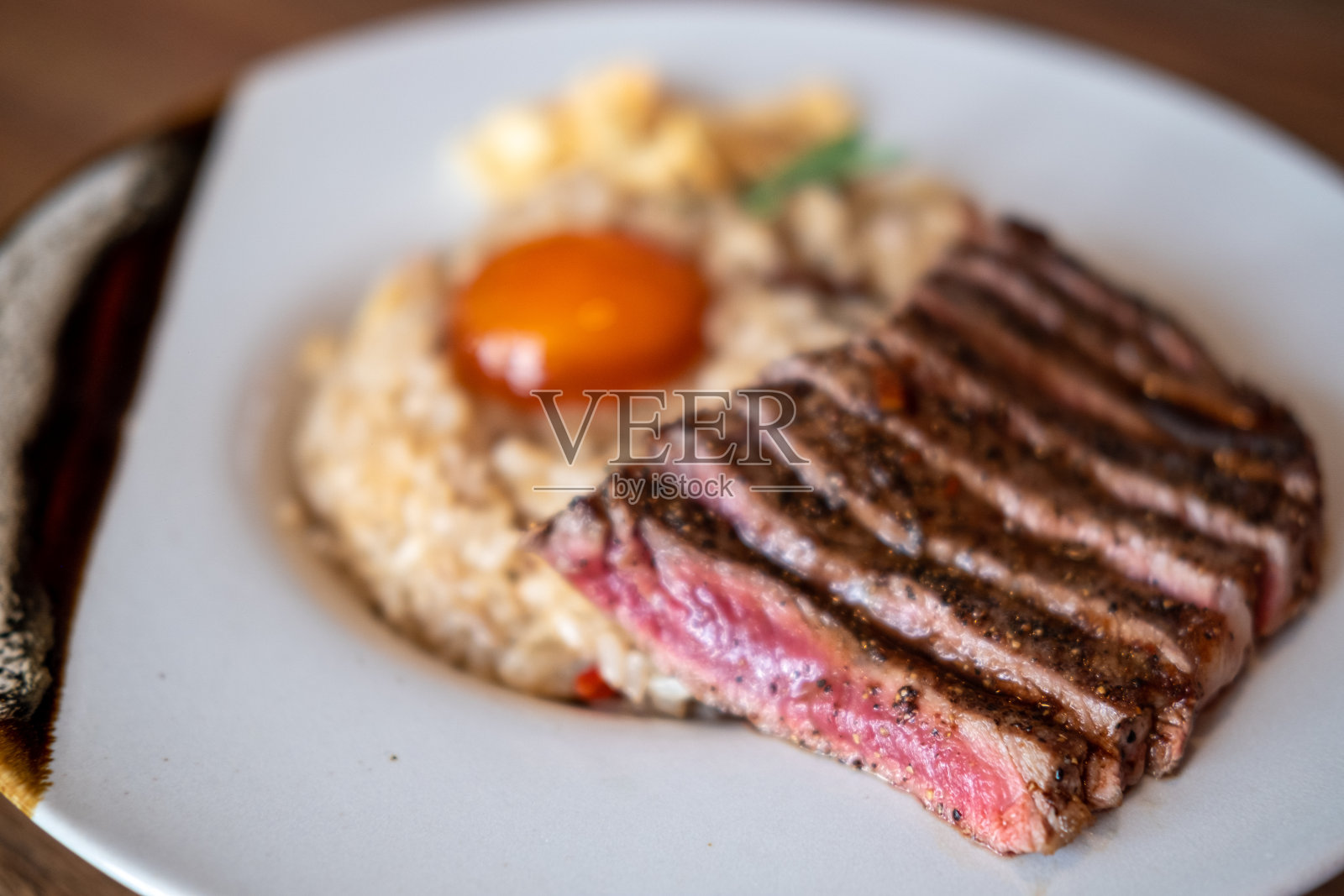 牛油炒饭，一碗米饭上放上半熟牛肉，配上蛋黄照片摄影图片