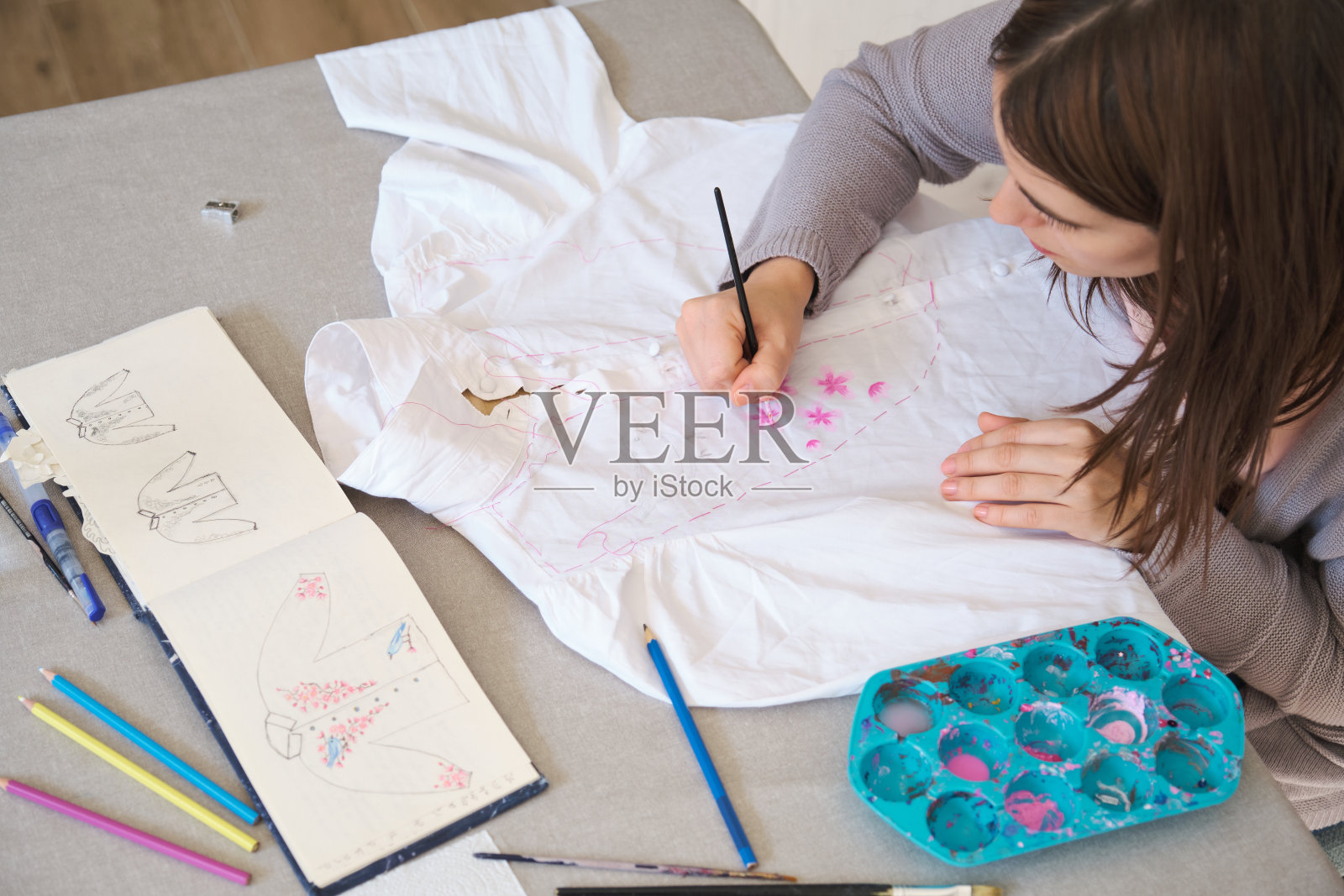 一个女人用丙烯酸颜料在衬衫上手绘设计的俯视图。照片摄影图片