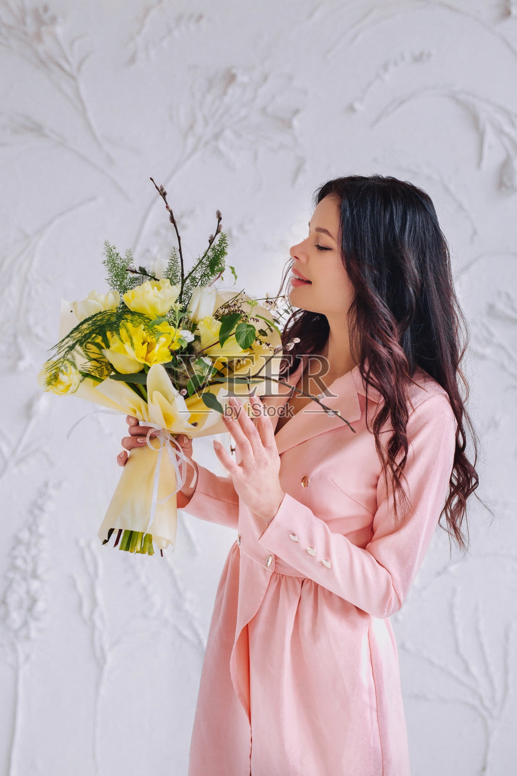 快乐的年轻女子穿着粉红色的裙子和郁金香花。性感的春天女人在工作室照片摄影图片