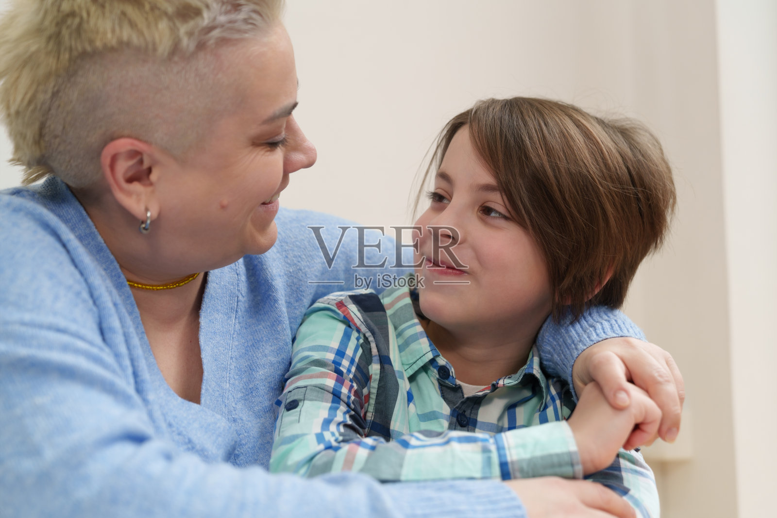 妈妈抱着她的小儿子。乌克兰幸福家庭的肖像。一个上小学的男孩和他妈妈坐在桌子后面照片摄影图片