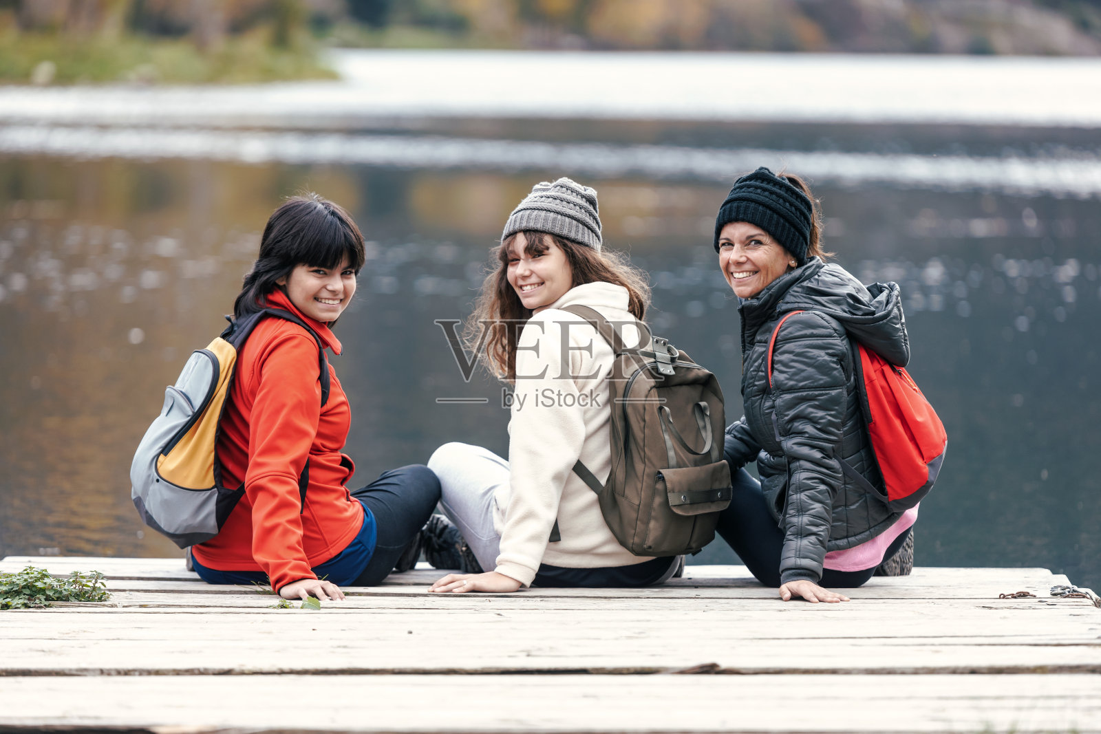 漂亮的家庭看着相机坐在码头上的湖照片摄影图片