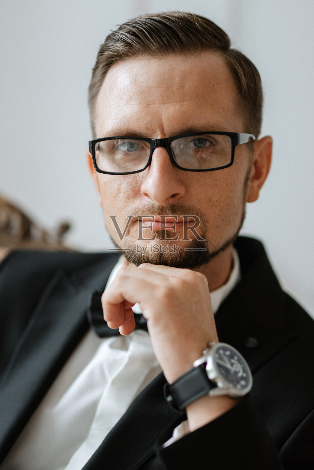 在画室里，身穿黑色西装、戴着眼镜的新郎的肖像照片摄影图片