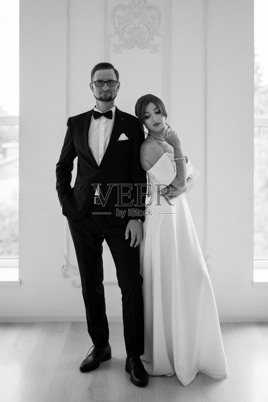 新郎系着黑色西装领带，新娘在明亮的画室里照片摄影图片