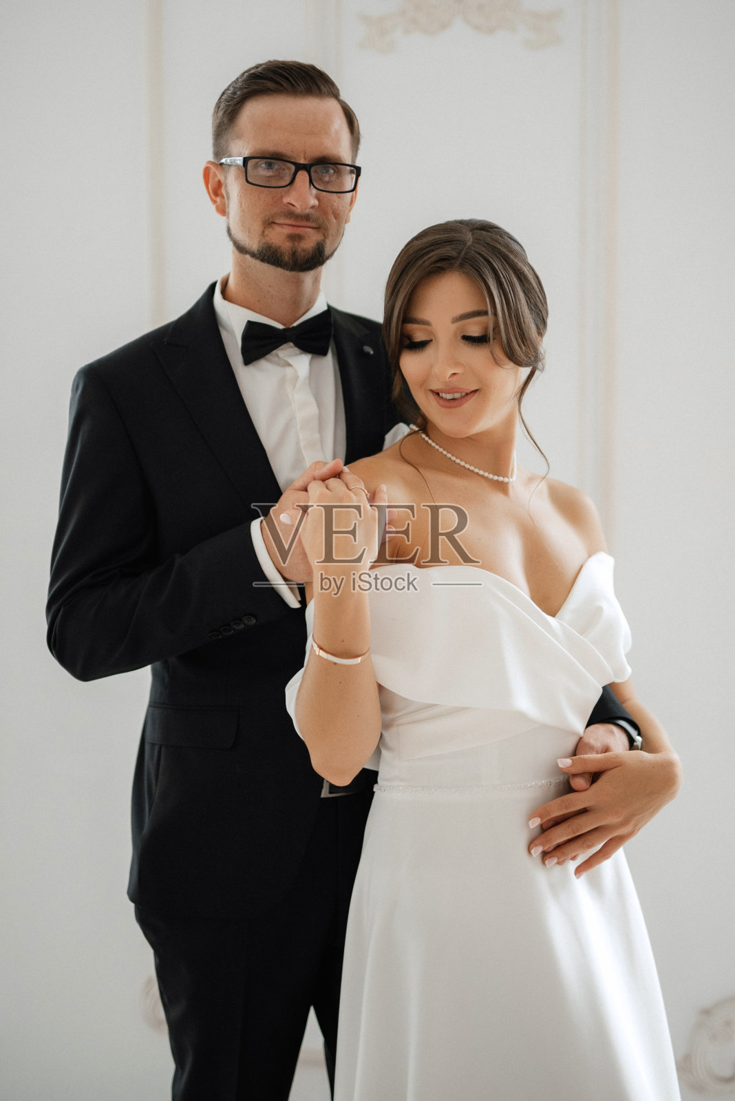 新郎系着黑色西装领带，新娘在明亮的画室里照片摄影图片