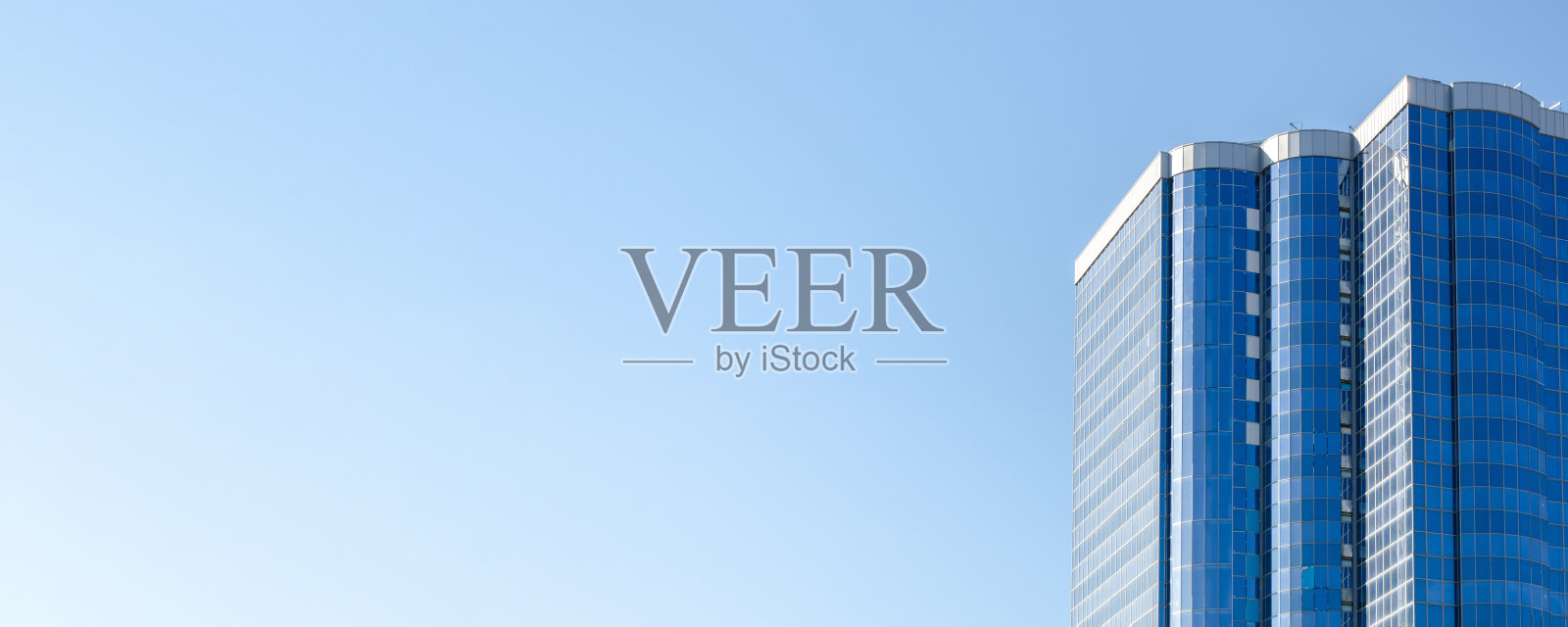 蓝色玻璃幕墙衬托蓝天的高层建筑。多层现代住宅建筑照片摄影图片