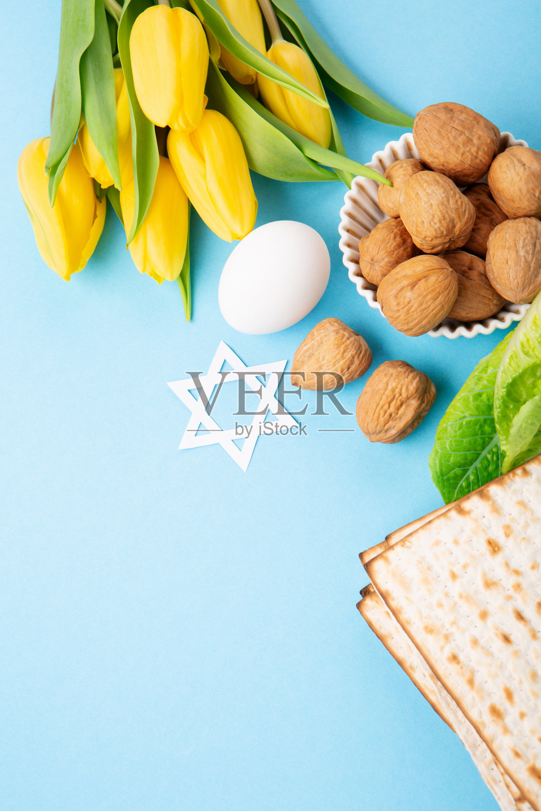 逾越节贺卡无酵饼，核桃和黄色郁金香花在蓝色的背景。照片摄影图片
