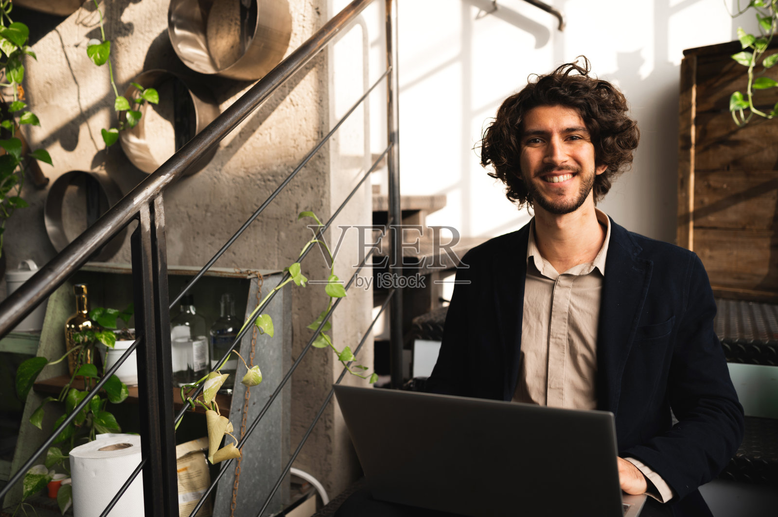 时髦的学生在镜头前微笑着摆姿势。一个人坐在休息室的楼梯上使用笔记本电脑照片摄影图片