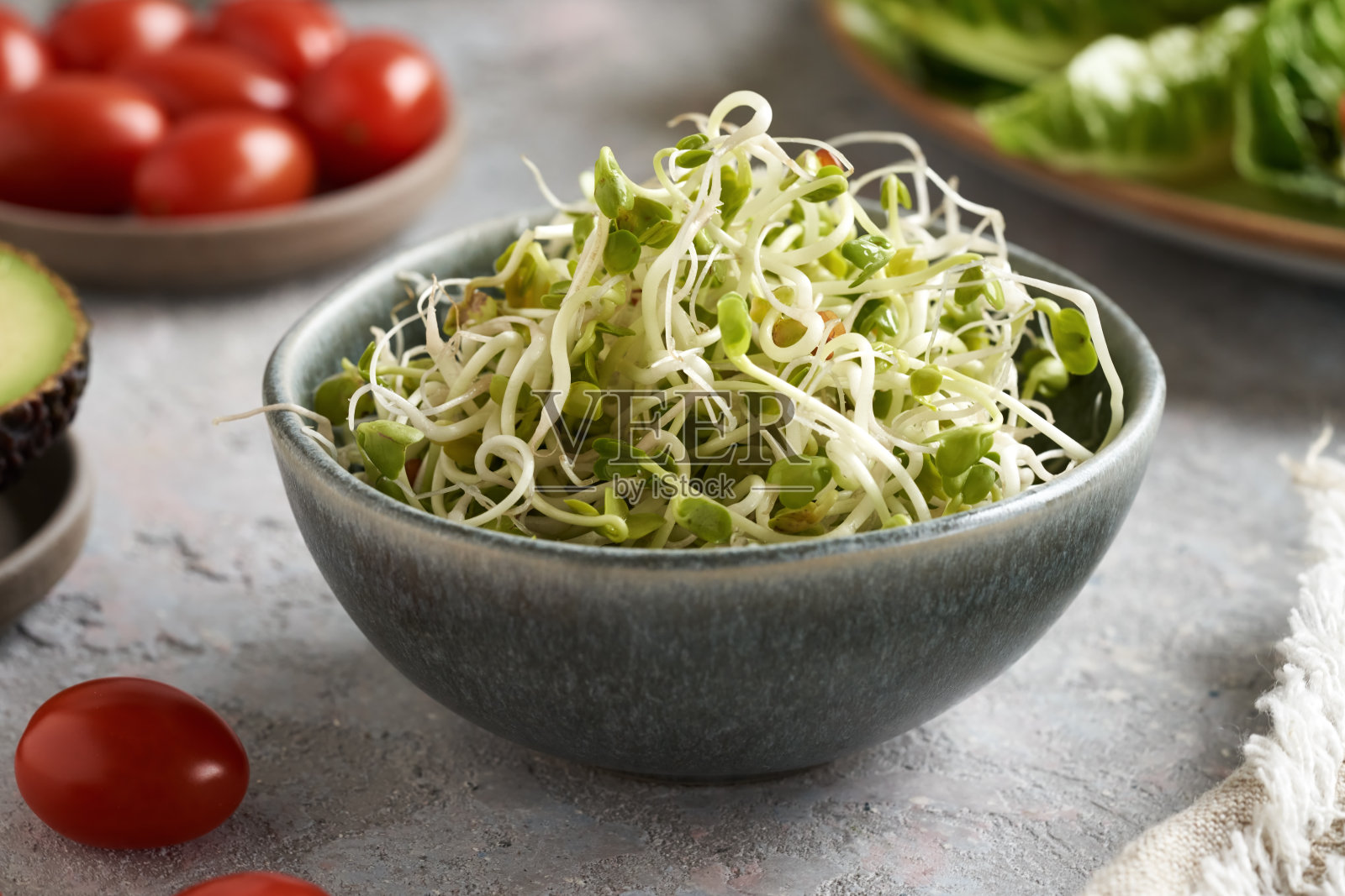 把萝卜芽放在碗里，配上西红柿和其他蔬菜照片摄影图片