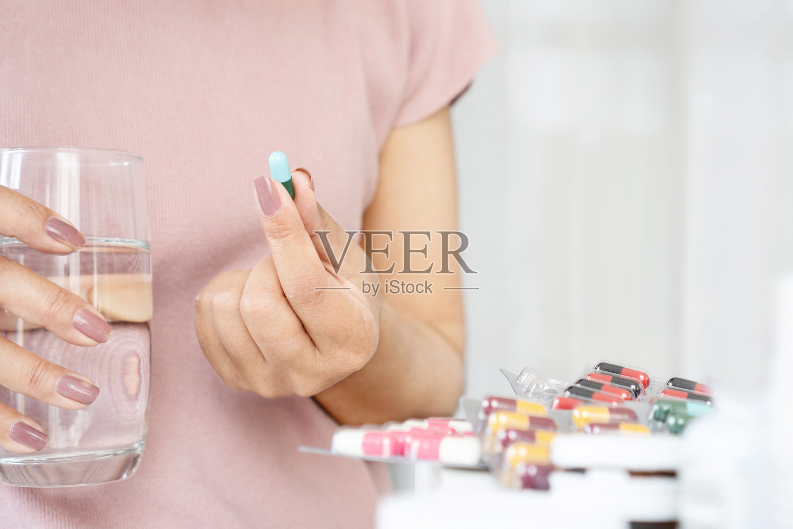 妇女用手拿着一杯水服用抗生素药片照片摄影图片
