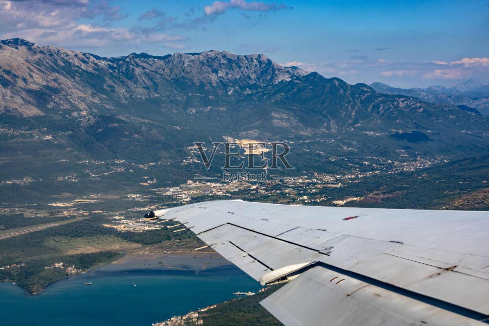在群山背景下飞行的飞机的机翼照片摄影图片