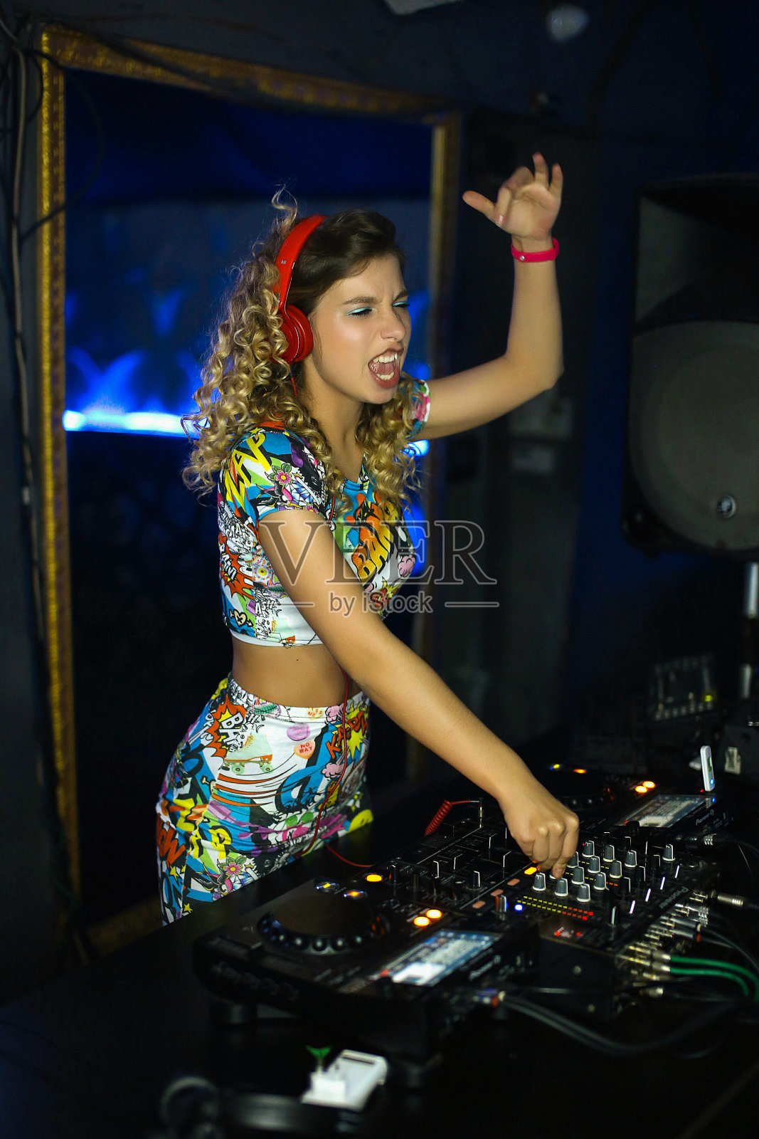 美丽积极的女孩DJ金发精力充沛的演奏和听音乐在夜总会，派对，在远程照片摄影图片