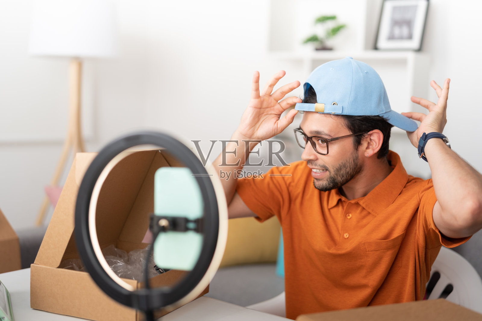 一名男子用他的手机为他的社交网络制作视频，试戴一顶帽子照片摄影图片