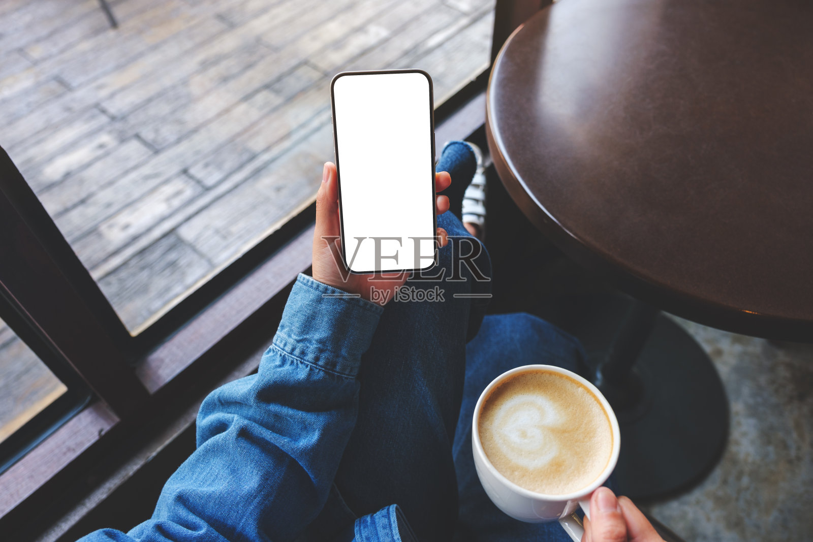 一个女人在咖啡馆里拿着空白屏幕和咖啡杯的手机的俯视图模型图像照片摄影图片