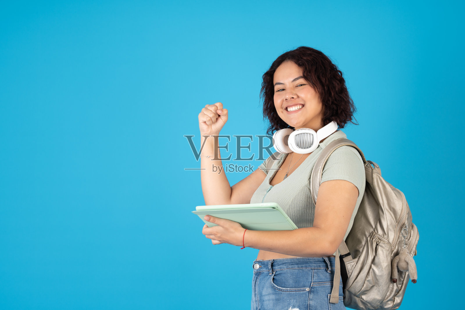 快乐而强大的大学女生背着背包，用着平板电脑照片摄影图片